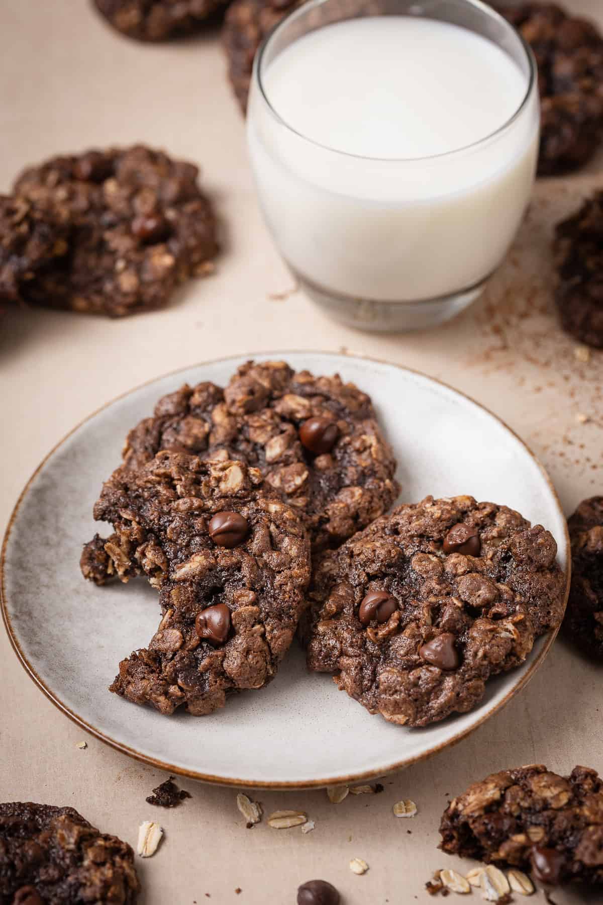 Chocolate oatmeal cookies with chocolate chips served with a glass of milk.