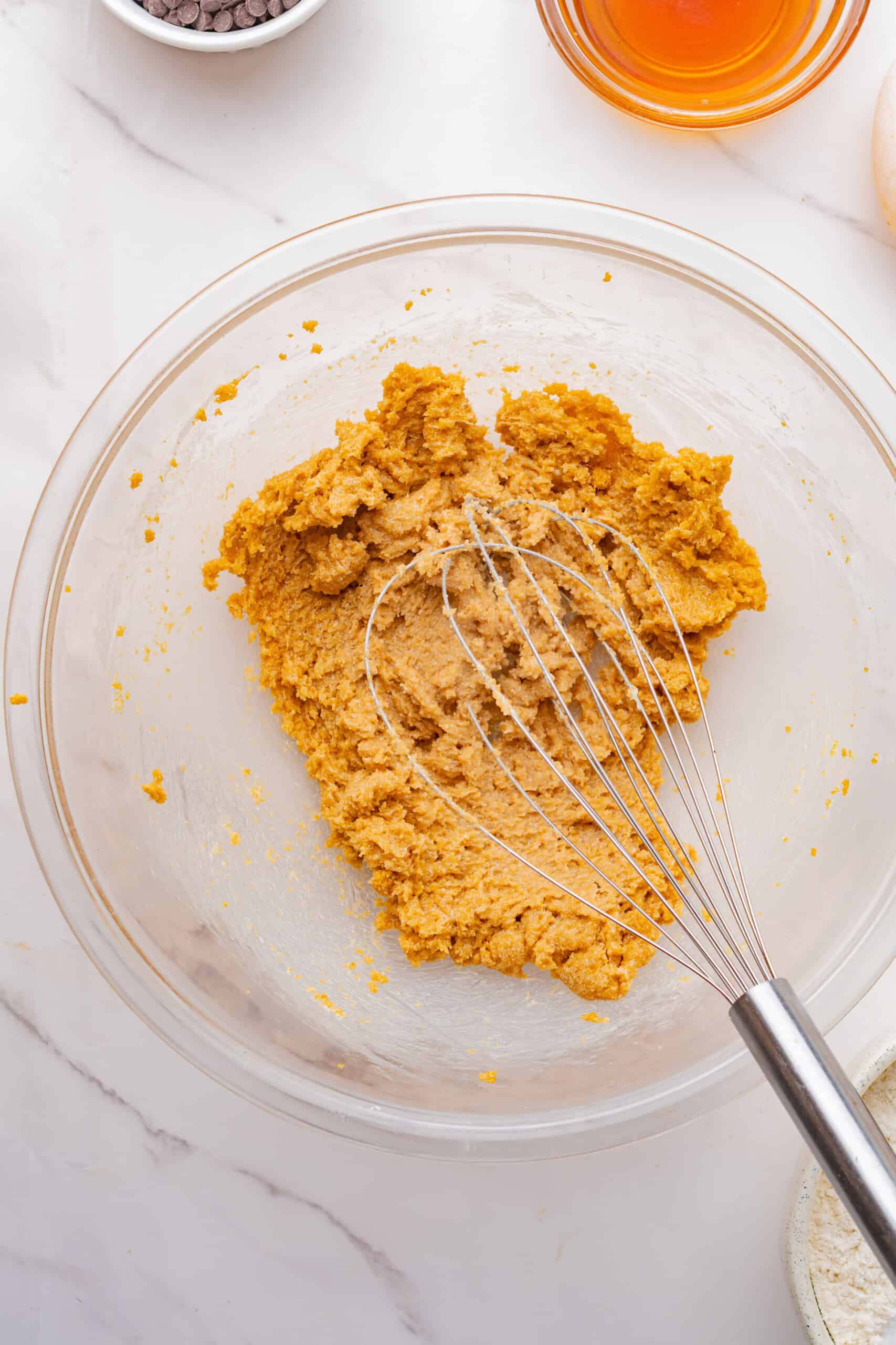 Creamed butter and brown sugar in a mixing bowl with a whisk.