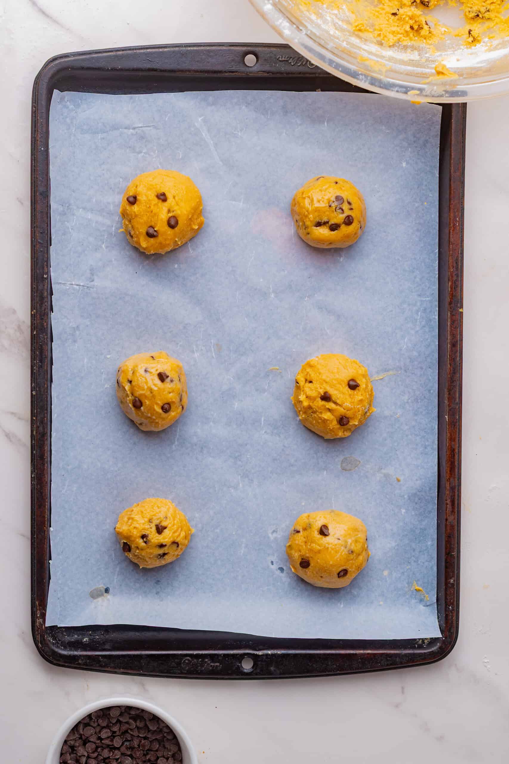 Maple chocolate chip cookie dough balls on a parchment-lined baking sheet.
