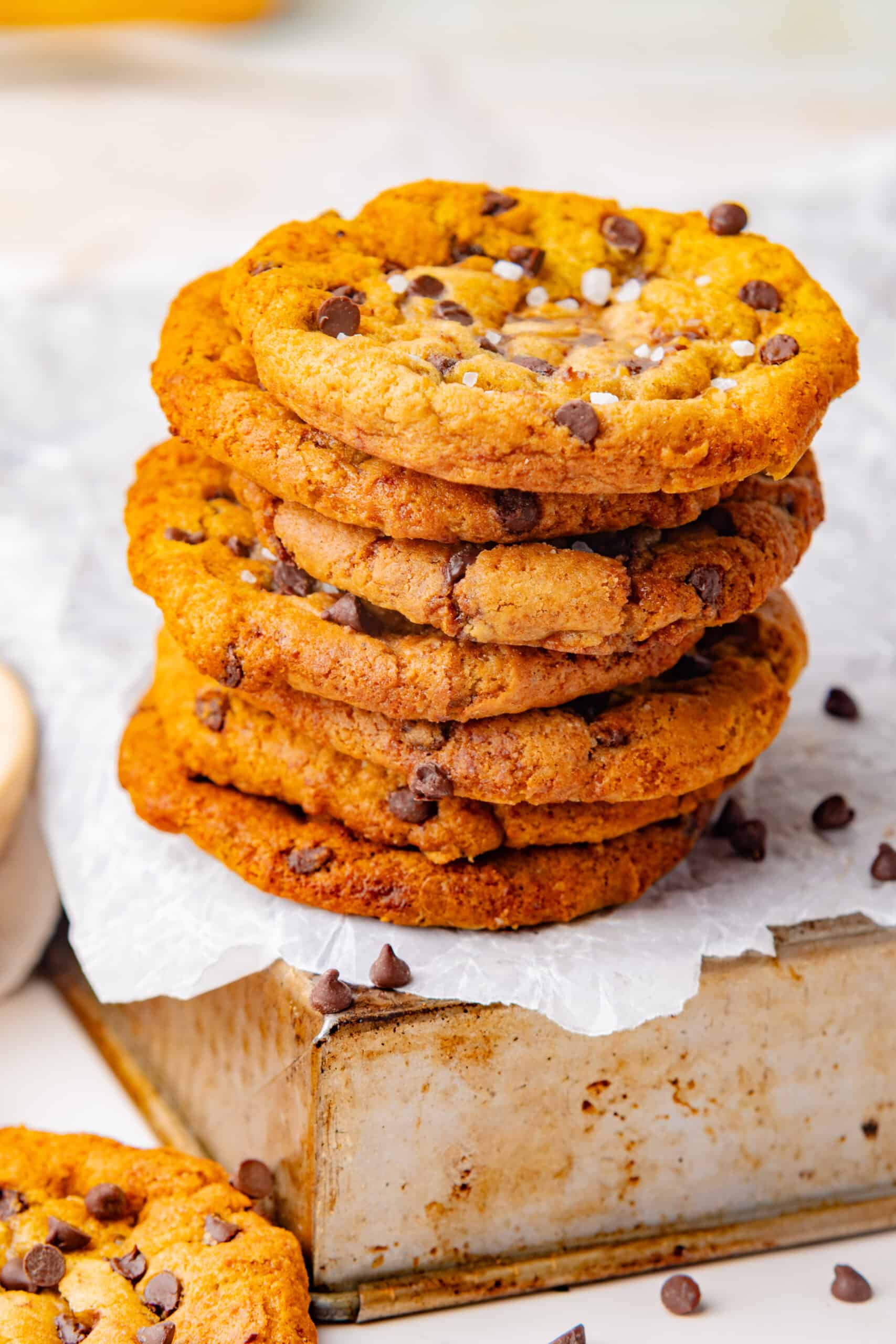 Stack of maple chocolate chip cookies topped with chocolate chips and flaky sea salt