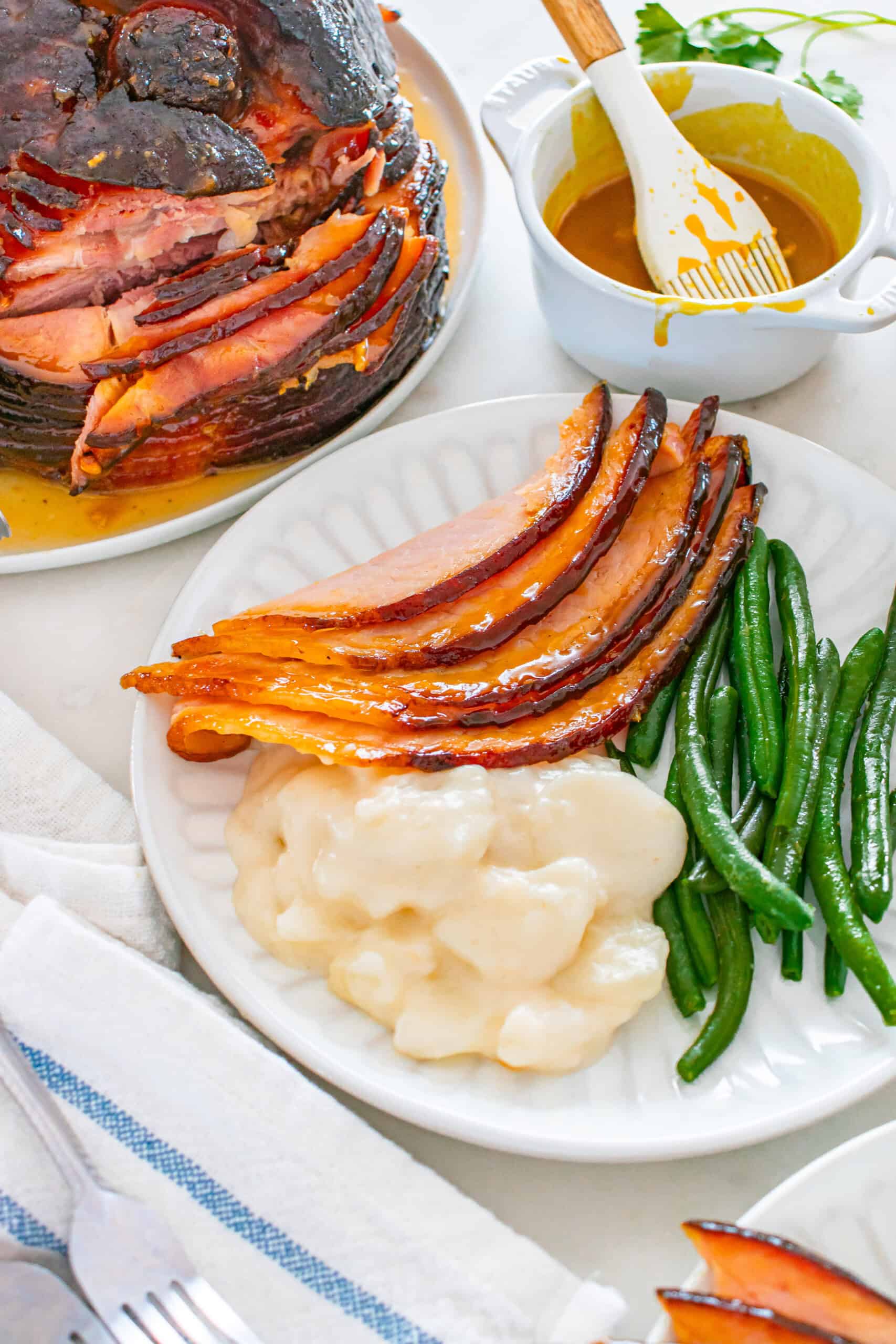Glazed baked ham slices served with creamy potatoes and green beans.