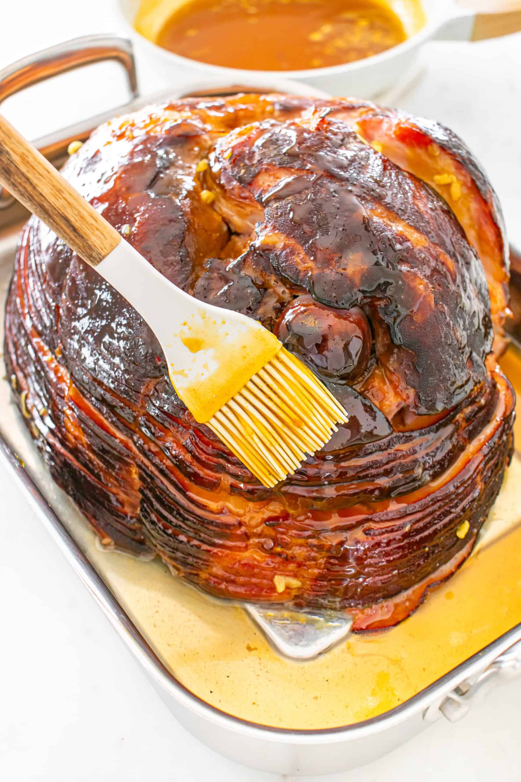 Glazing a spiral ham with a basting brush