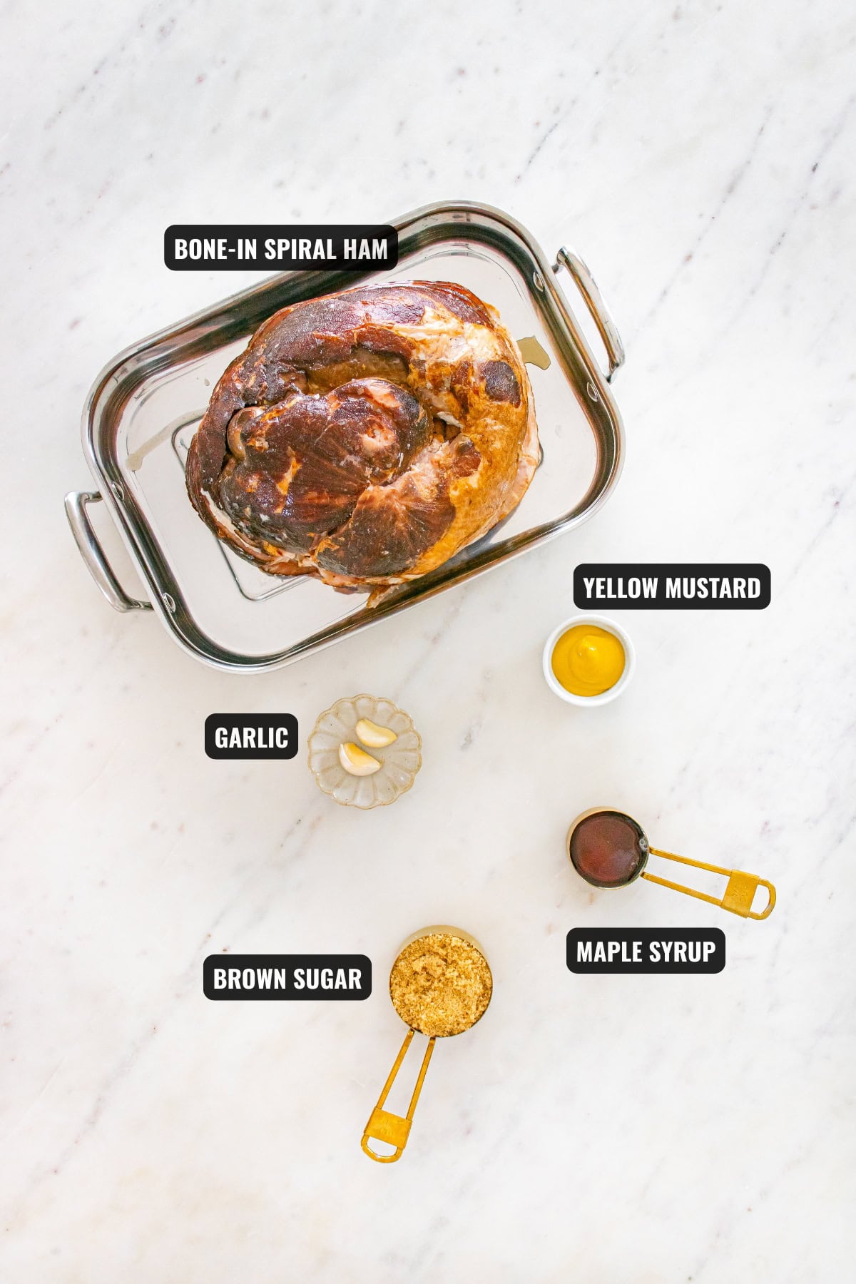 ingredients for baked ham recipe including spiral ham, yellow mustard, brown sugar, maple syrup, and garlic
