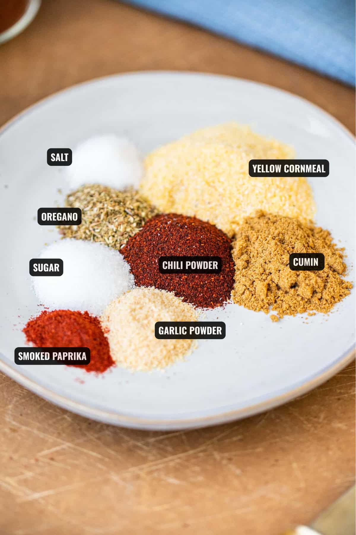 ingredients for taco seasoning including yellow cornmeal, oregano, cumin, chili powder, garlic powder, smoked paprika, sugar, and salt