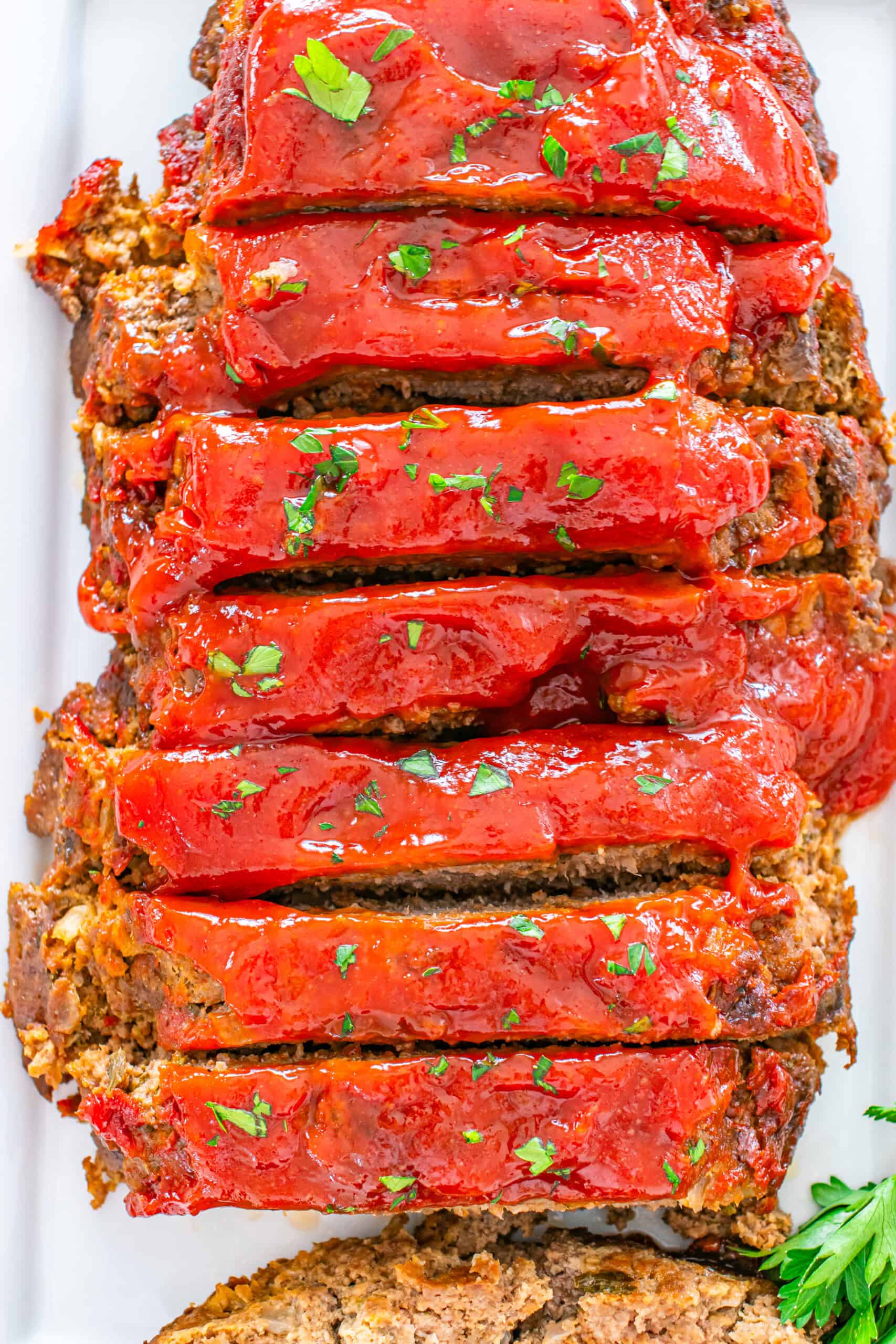 Sliced meatloaf topped with glaze and fresh parsley.