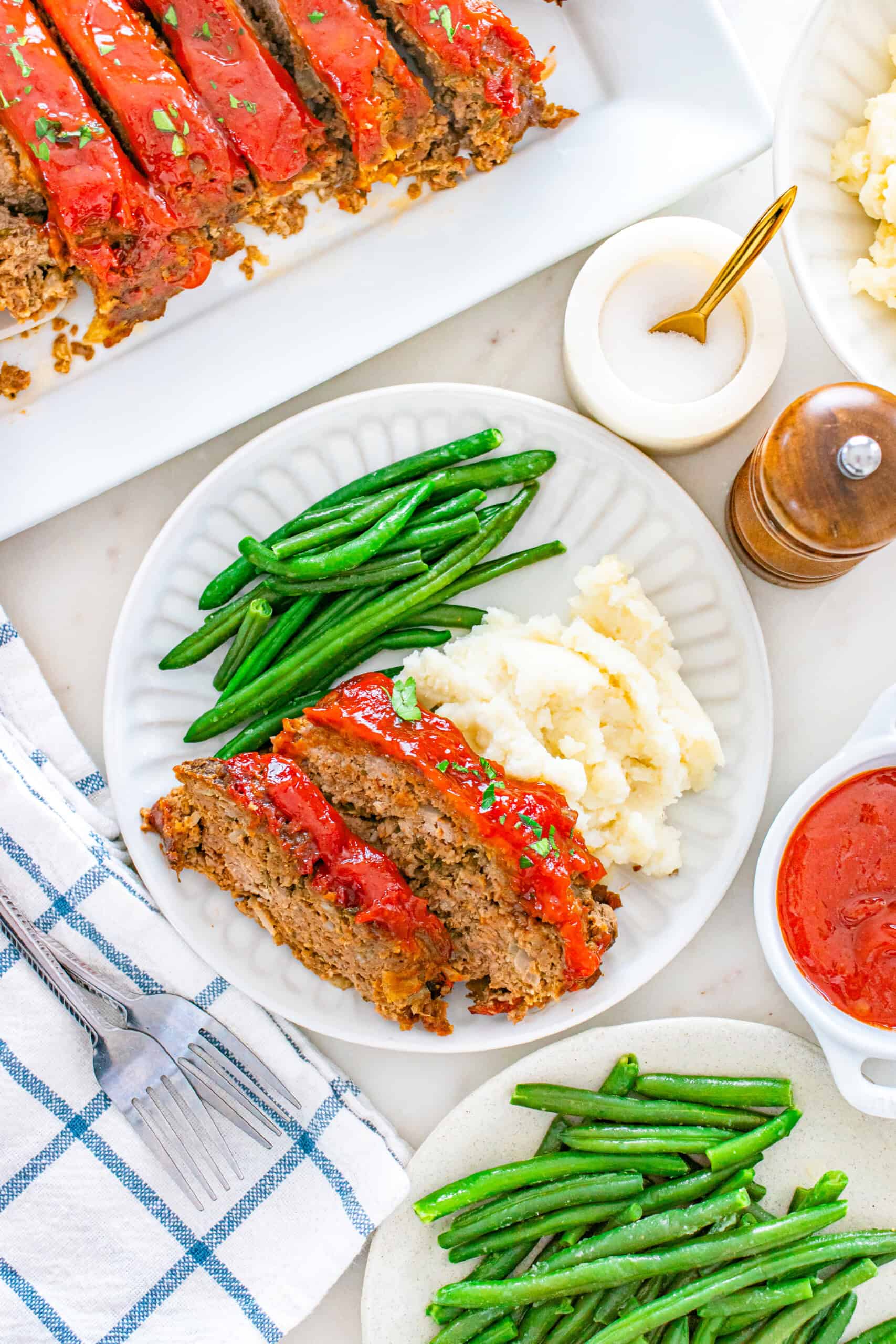 Glazed moist meatloaf slices served with mashed potatoes and green beans.