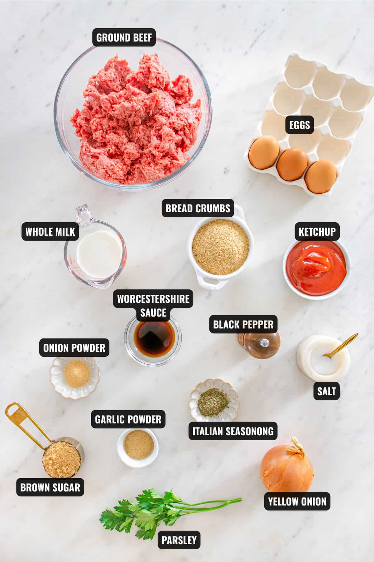 ingredients for moist meatloaf recipe including ground beef, eggs, whole milk, bread crumbs, worcestershire sauce, black pepper, yellow onion, parsley, italian seasoning, onion powder, garlic powder. ketchup, and brown sugar.