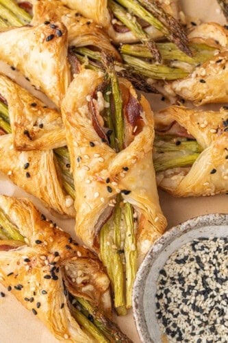 Golden asparagus puff pastry bundles with pancetta and sesame seeds.