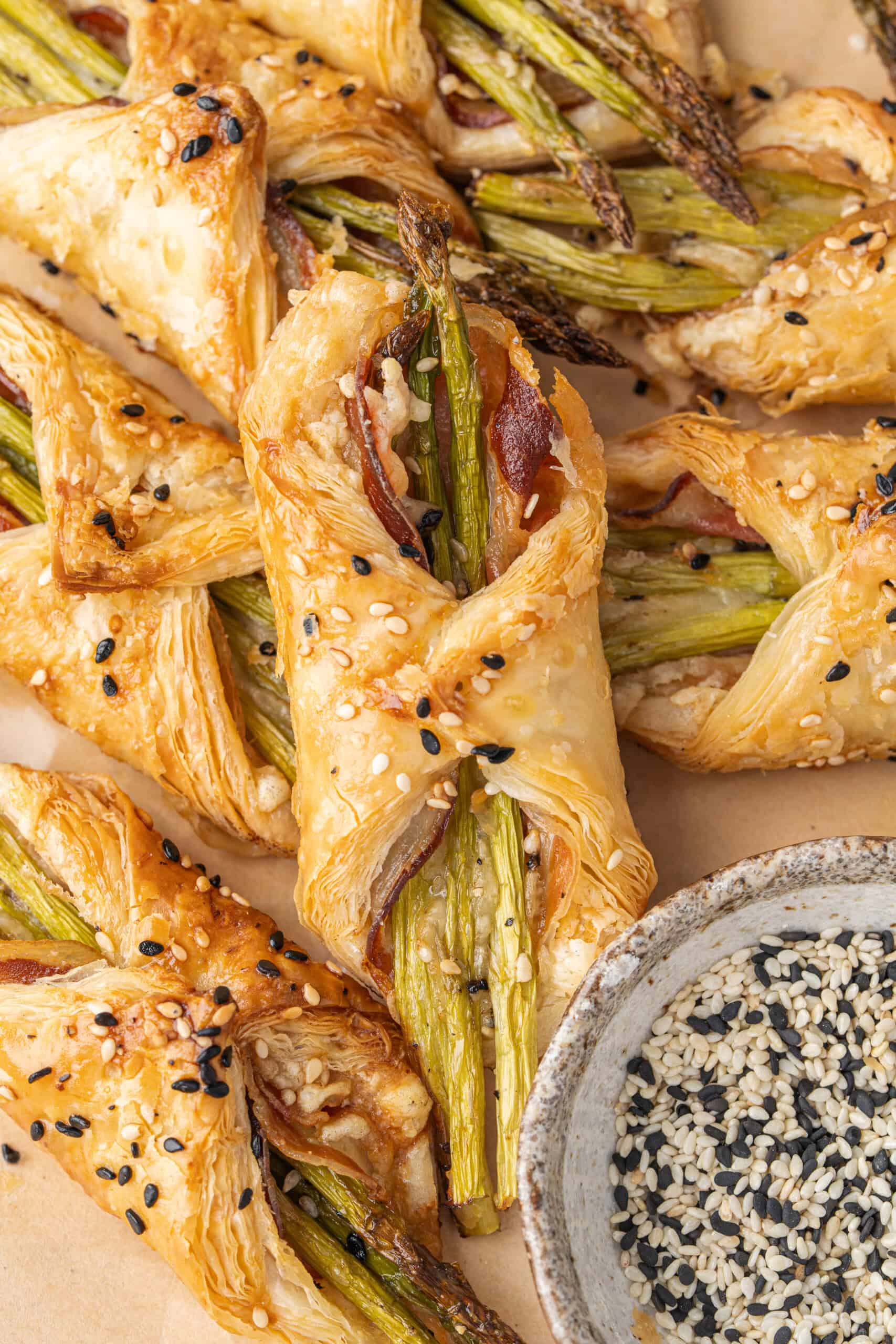 Golden asparagus puff pastry bundles with pancetta and sesame seeds.