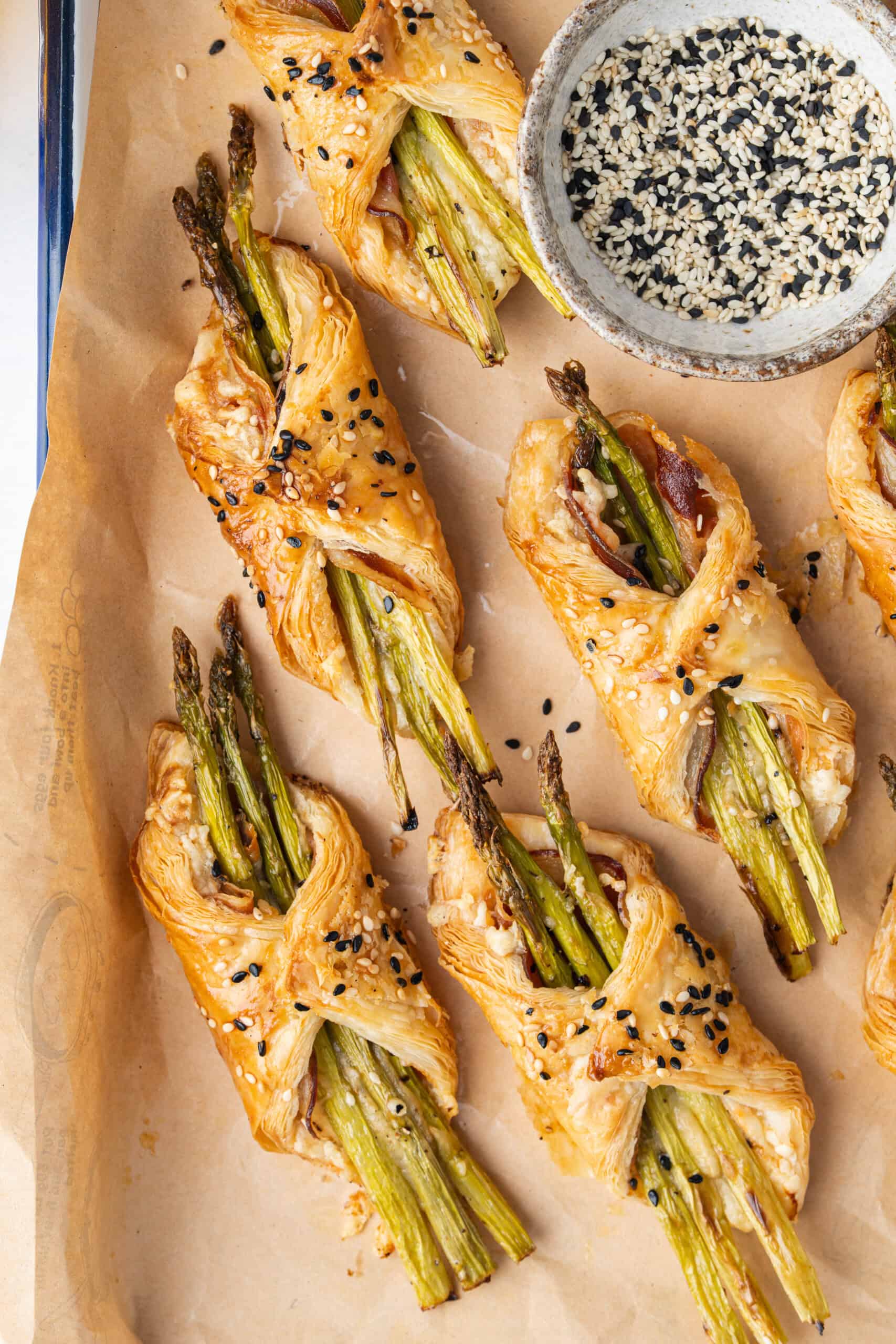 Golden asparagus bundles with pancetta and sesame seeds on parchment paper