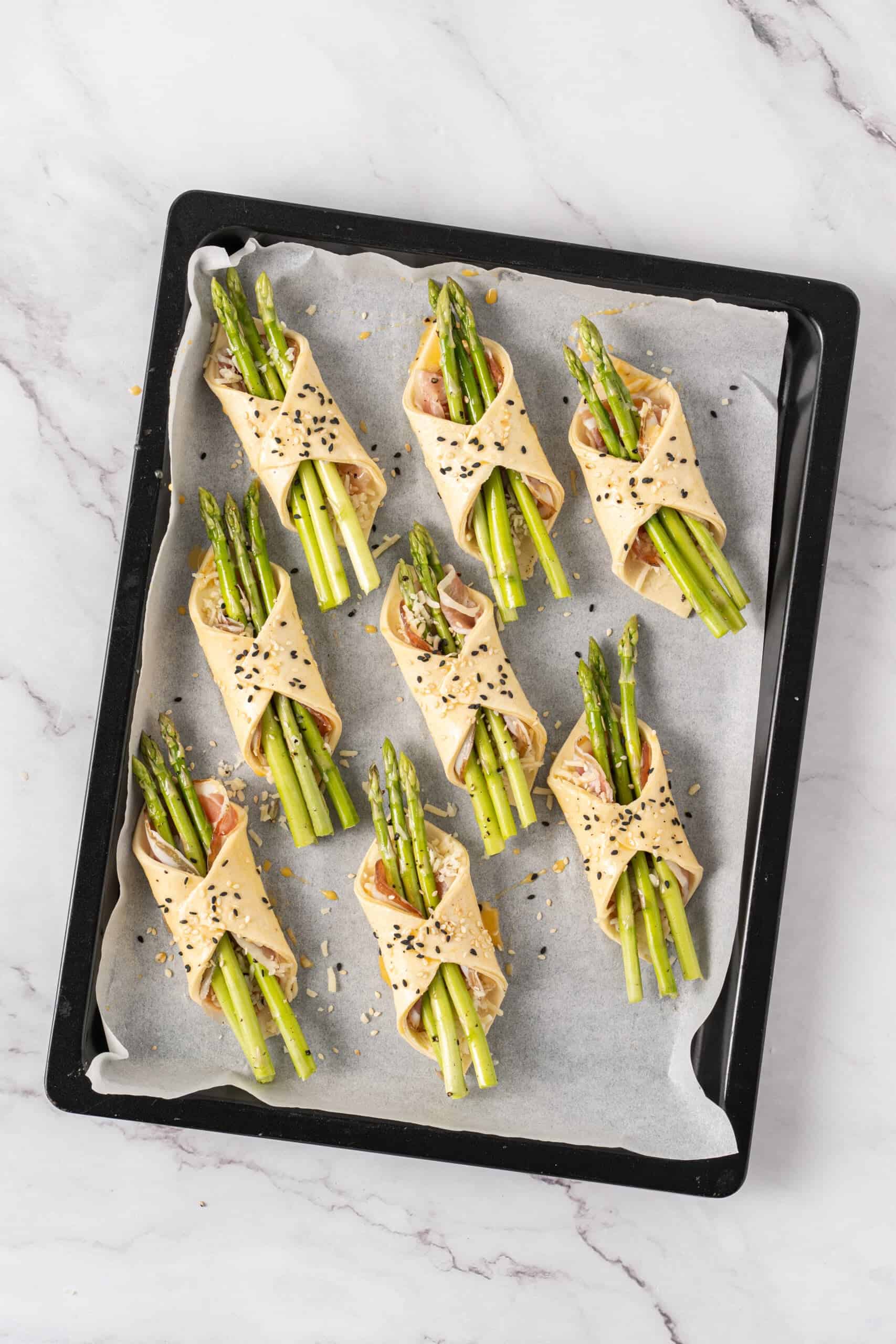 Asparagus bundles sprinkled with sesame seeds and ready to bake.