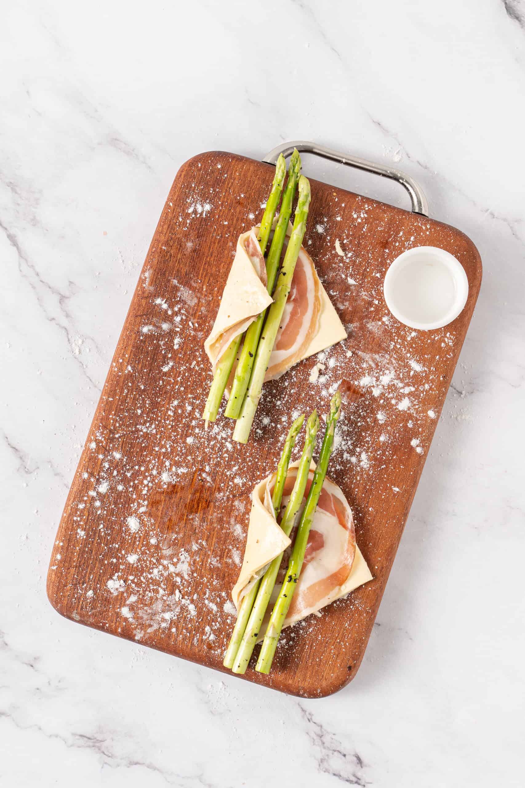 Puff pastry wrapped around pancetta and seasoned asparagus spears before baking.
