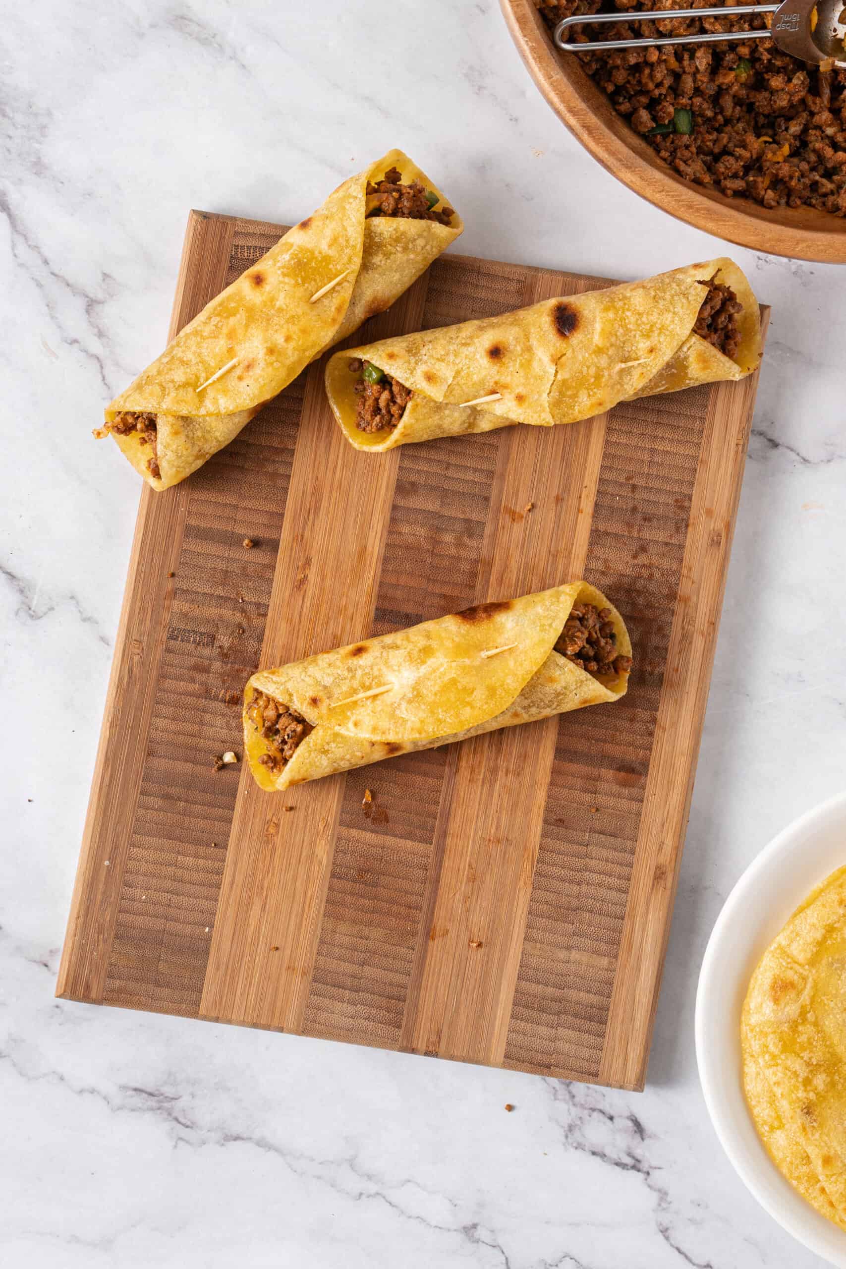 Beef taquitos rolled in corn tortillas and secured with toothpicks.