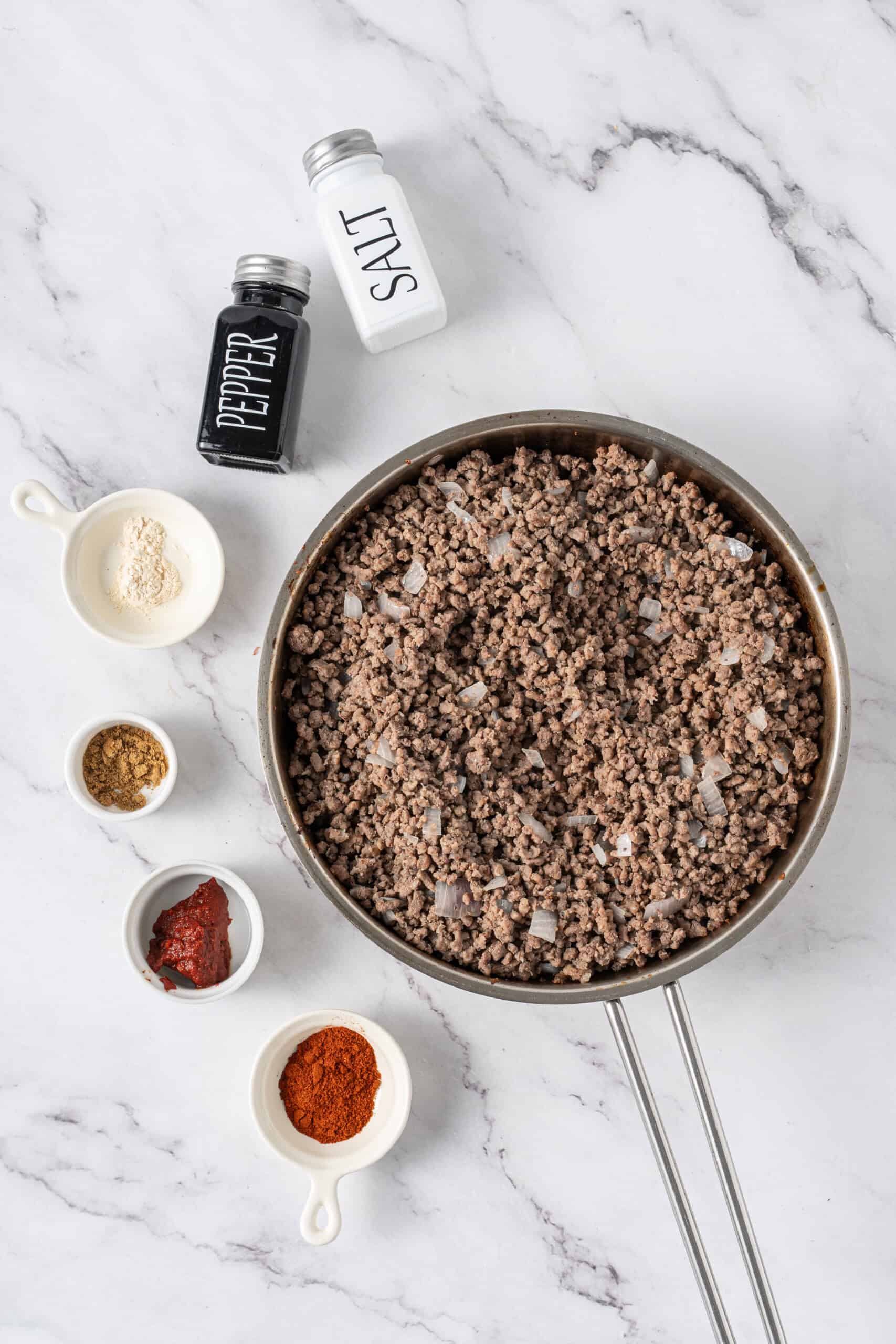 Cooked ground beef and onions with seasonings ready to be added.