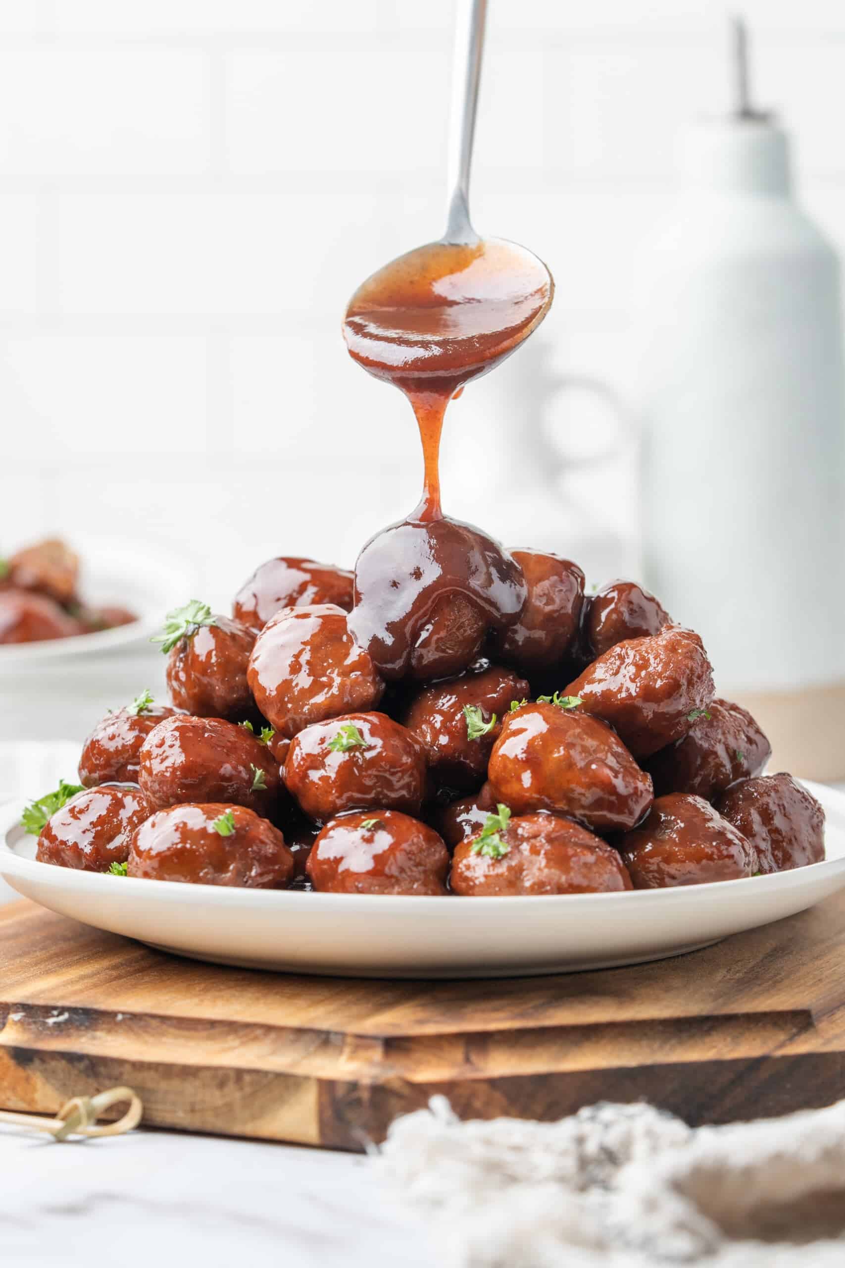 Grape jelly meatballs drizzled with glossy sauce and garnished with fresh parsley.