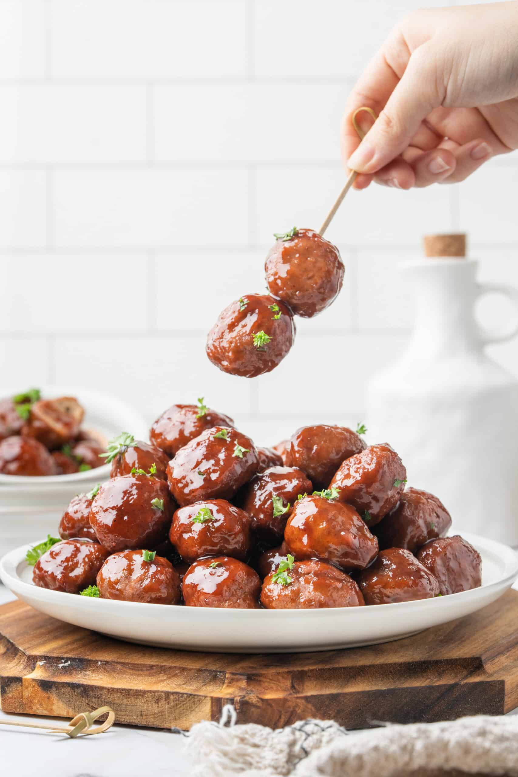 meatballs on skewers, coated in glossy sauce and garnished with fresh parsley.
