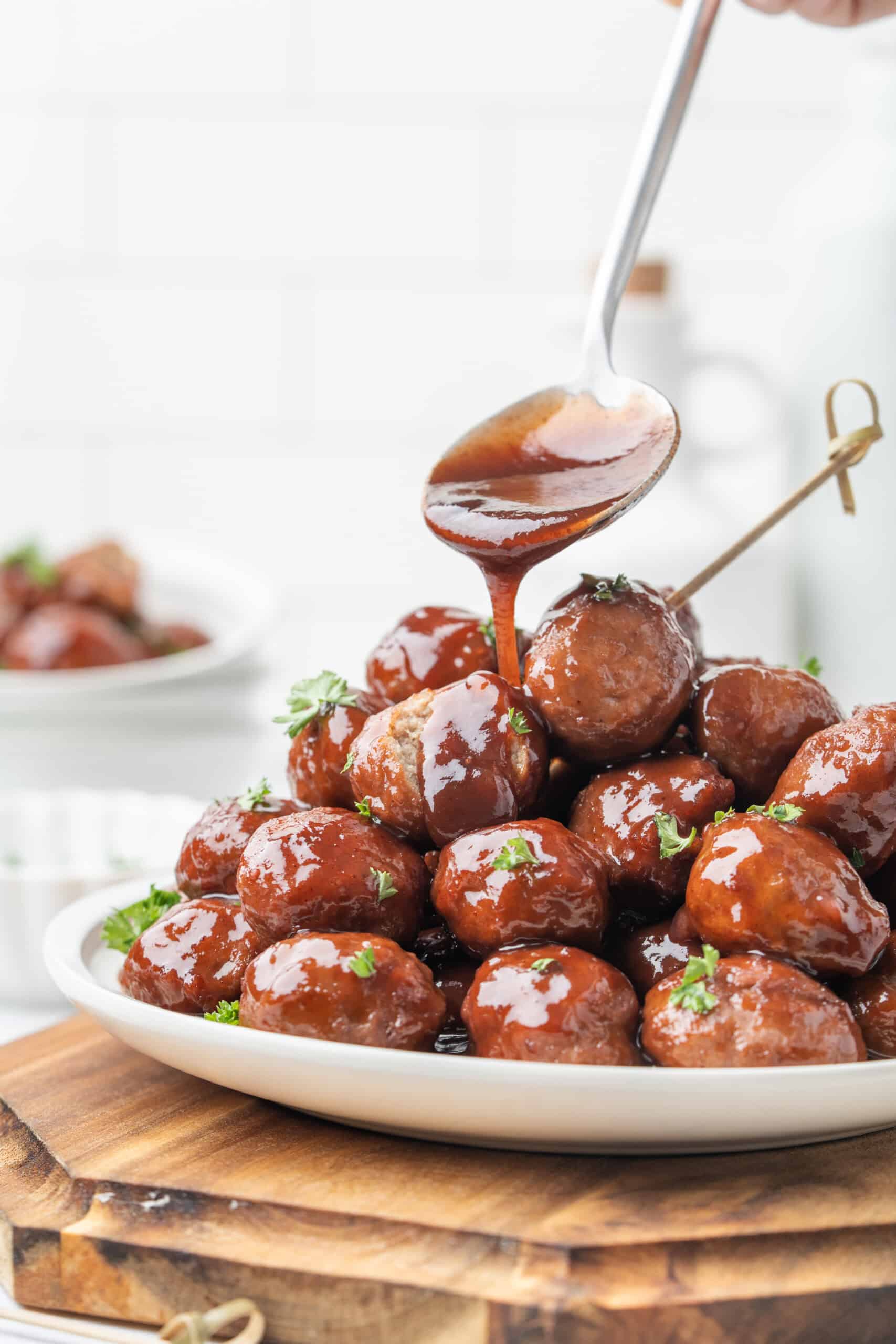 Grape jelly meatballs topped with glossy sauce and fresh parsley on a serving platter.