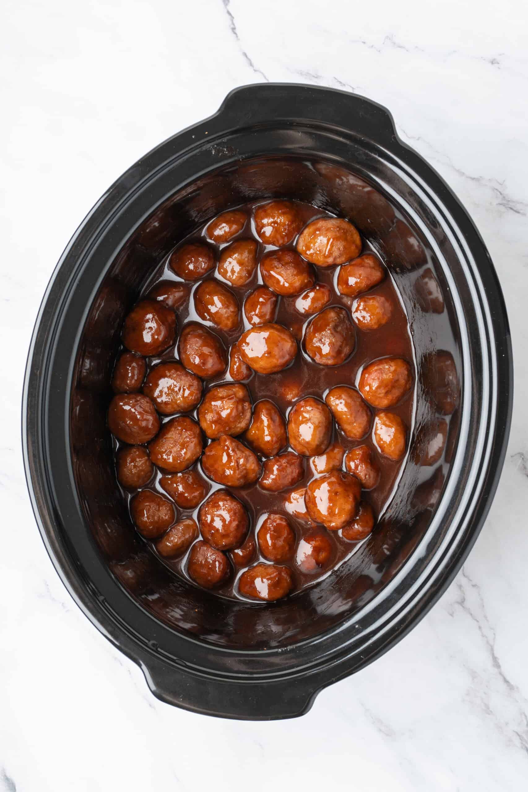meatballs coated in a glossy chili sauce in a slow cooker.