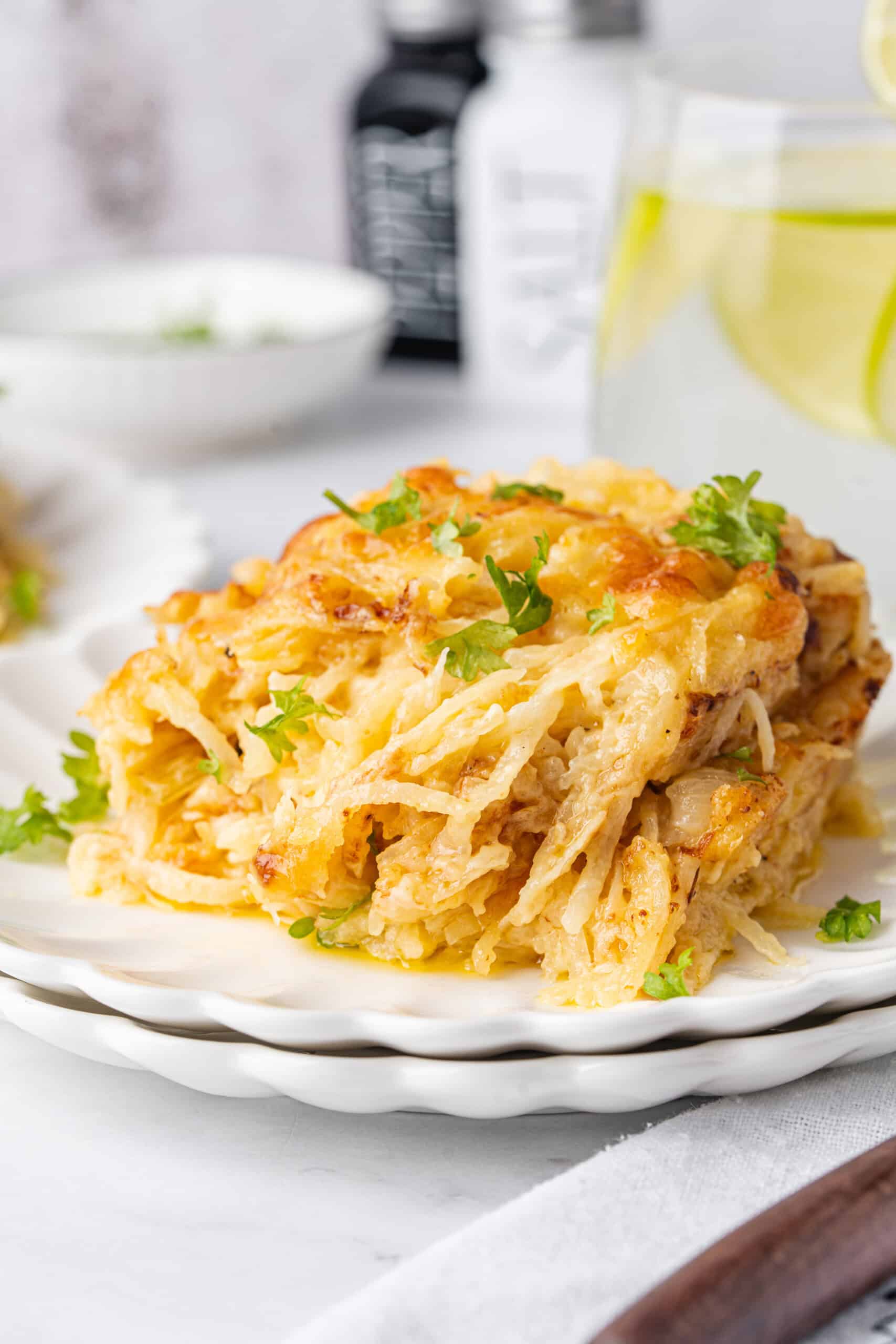 Casserole with golden melted cheese and fresh parsley on a white plate