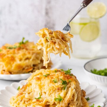 Hashbrown casserole with golden cheese, fresh parsley, and a forkful lifted from the plate