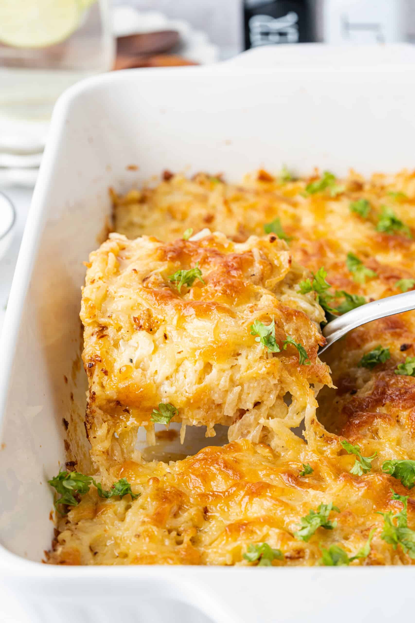 Cheesy potato casserole with golden melted cheese and parsley being served from a baking dish