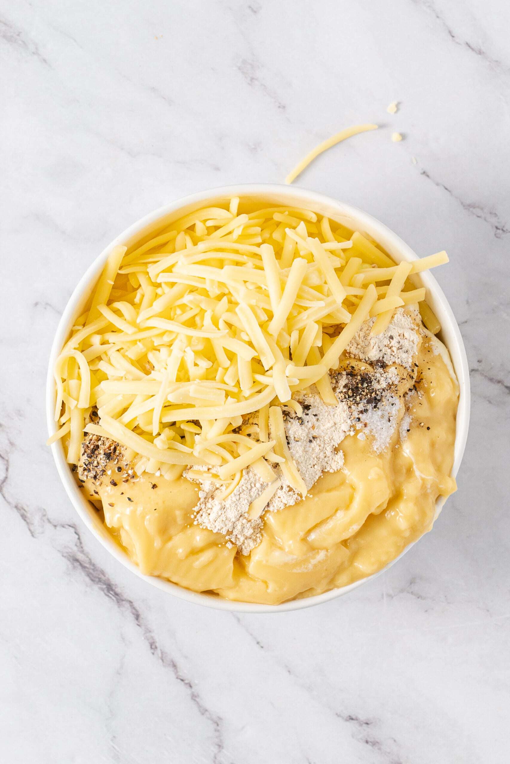 Shredded cheese, creamy soup, and seasonings in a bowl