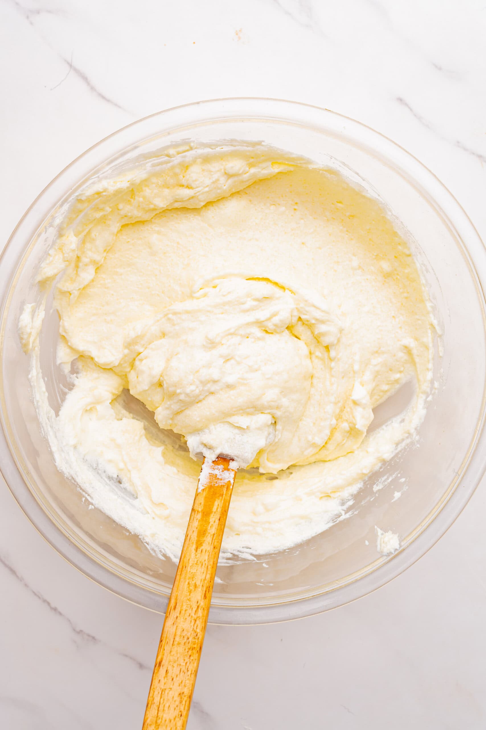 Cream cheese and sugar mixed together until creamy in a glass bowl.