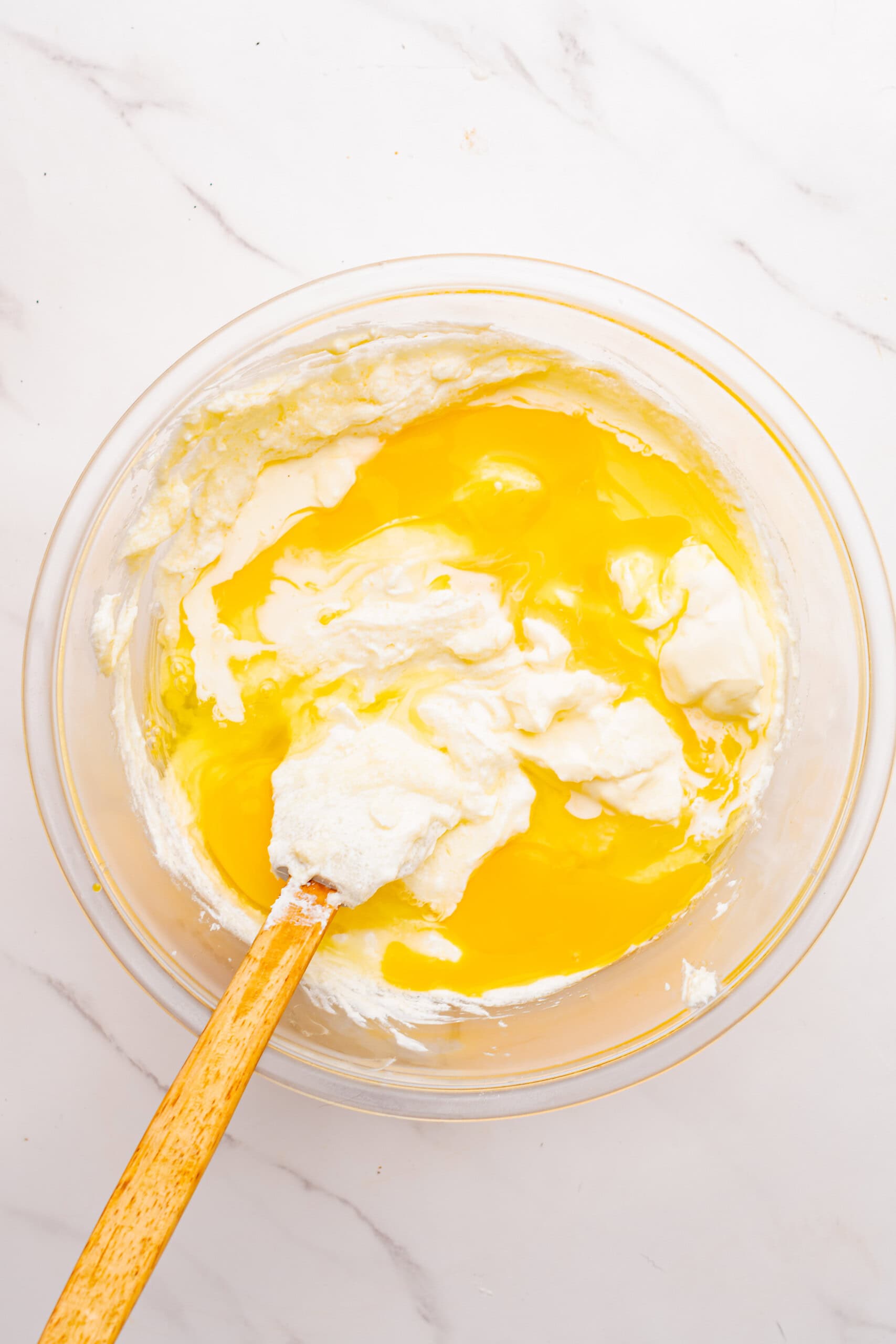 Beaten eggs added to the cream cheese mixture in a glass mixing bowl