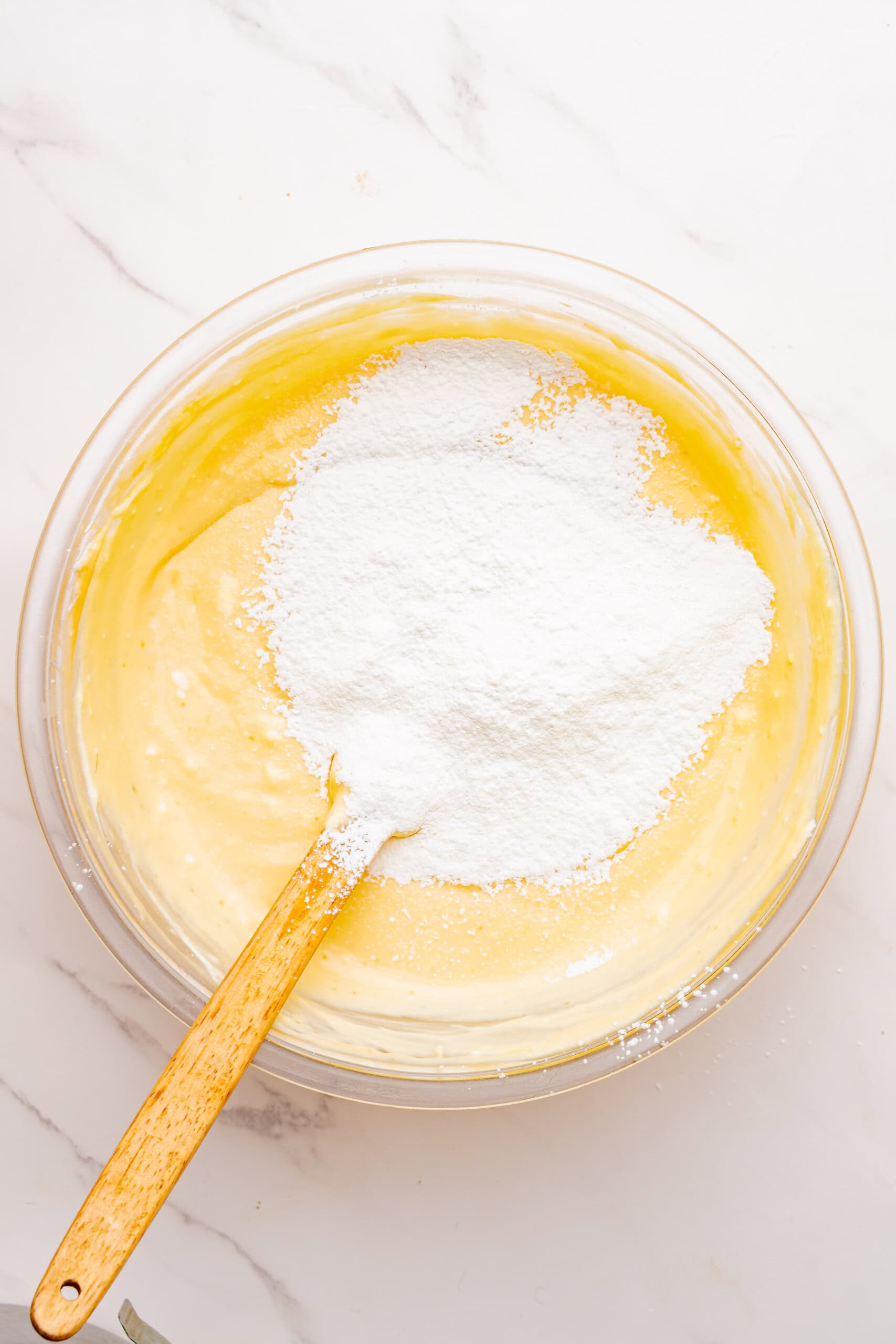 Cornstarch added to the cheesecake filling in a glass mixing bowl.