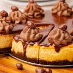 cheesecake sliced into wedges with chocolate ganache, chocolate whipped cream, and chocolate-covered candies.