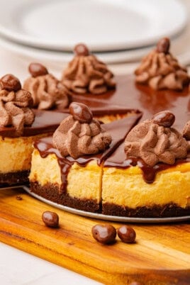 cheesecake sliced into wedges with chocolate ganache, chocolate whipped cream, and chocolate-covered candies.