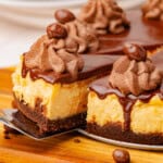 Slice of Irish cream cheesecake topped with chocolate ganache, chocolate whipped cream, and chocolate-covered candies.