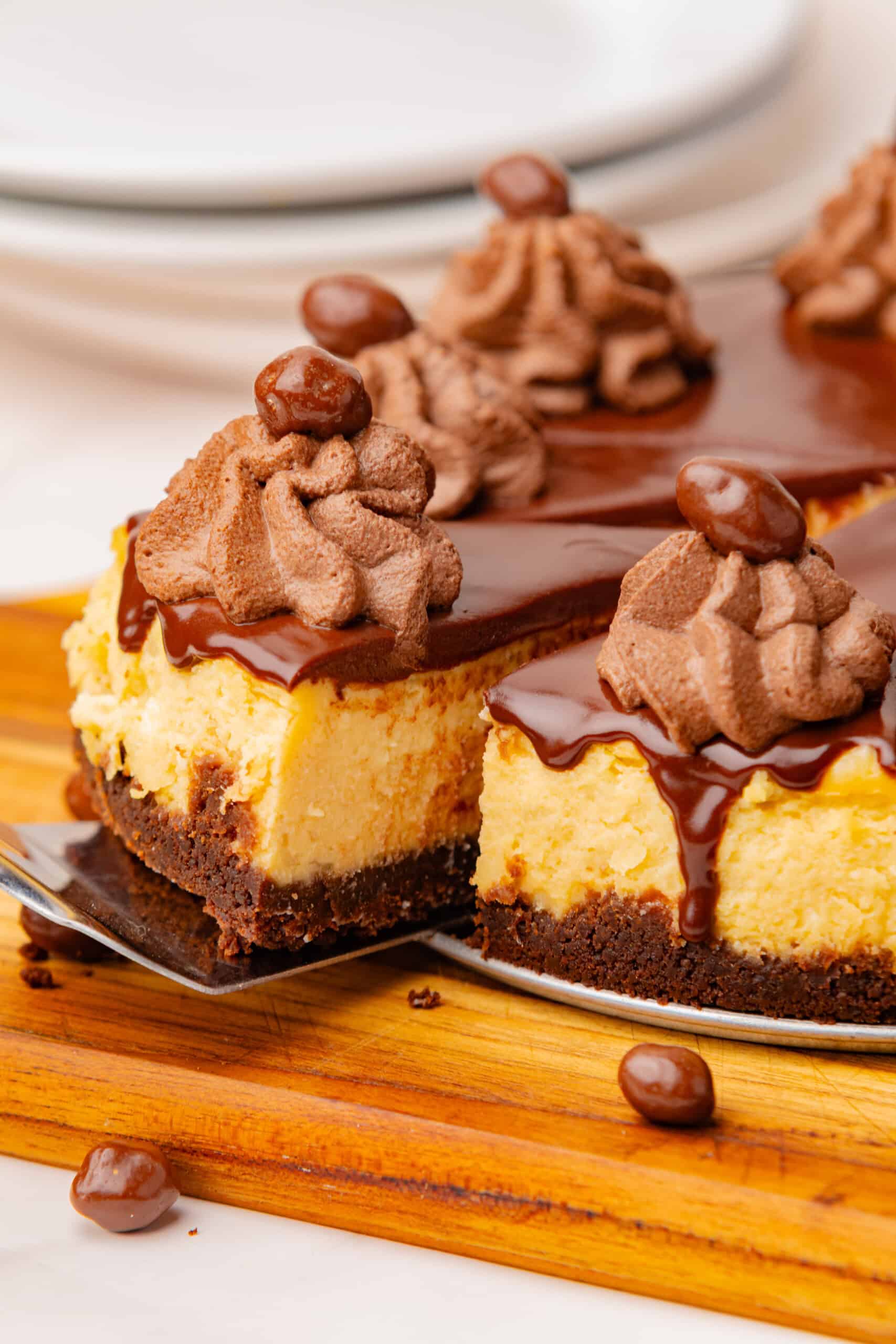 Slice of Irish cream cheesecake topped with chocolate ganache, chocolate whipped cream, and chocolate-covered candies.