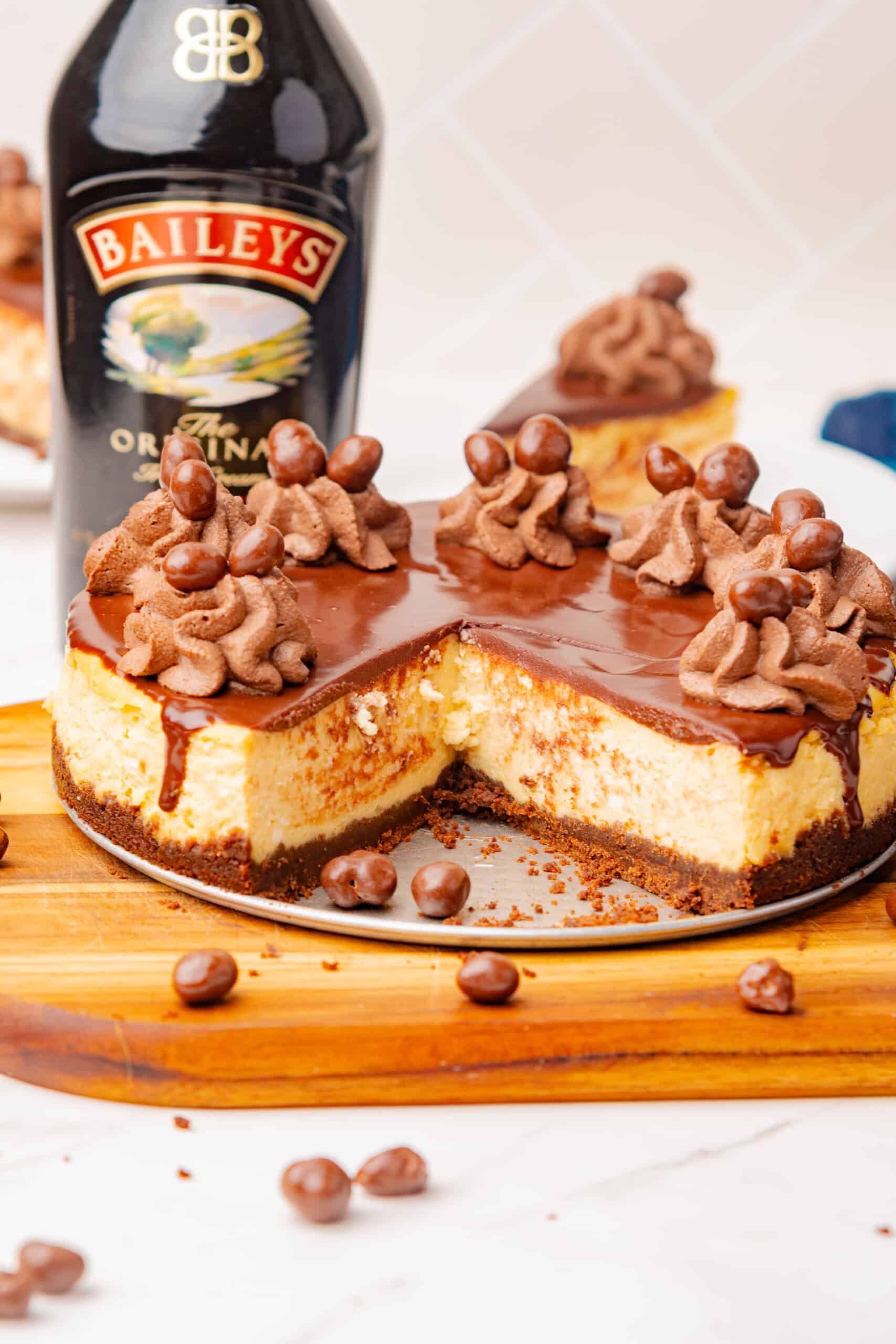 Baileys Irish cream cheesecake with chocolate ganache, chocolate whipped cream, and a slice removed.