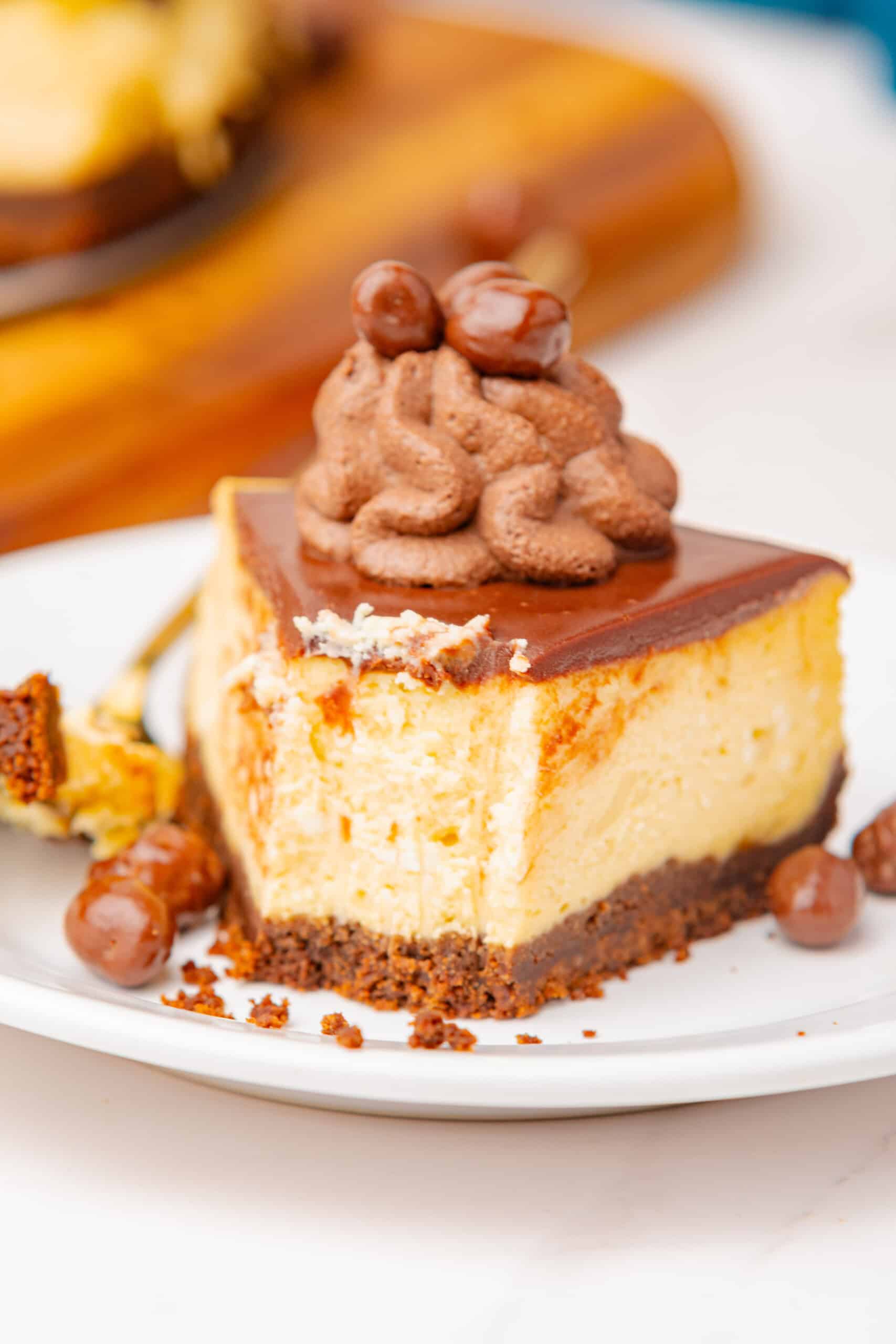 Slice of cheesecake with chocolate ganache, chocolate whipped cream, and chocolate-covered candies.