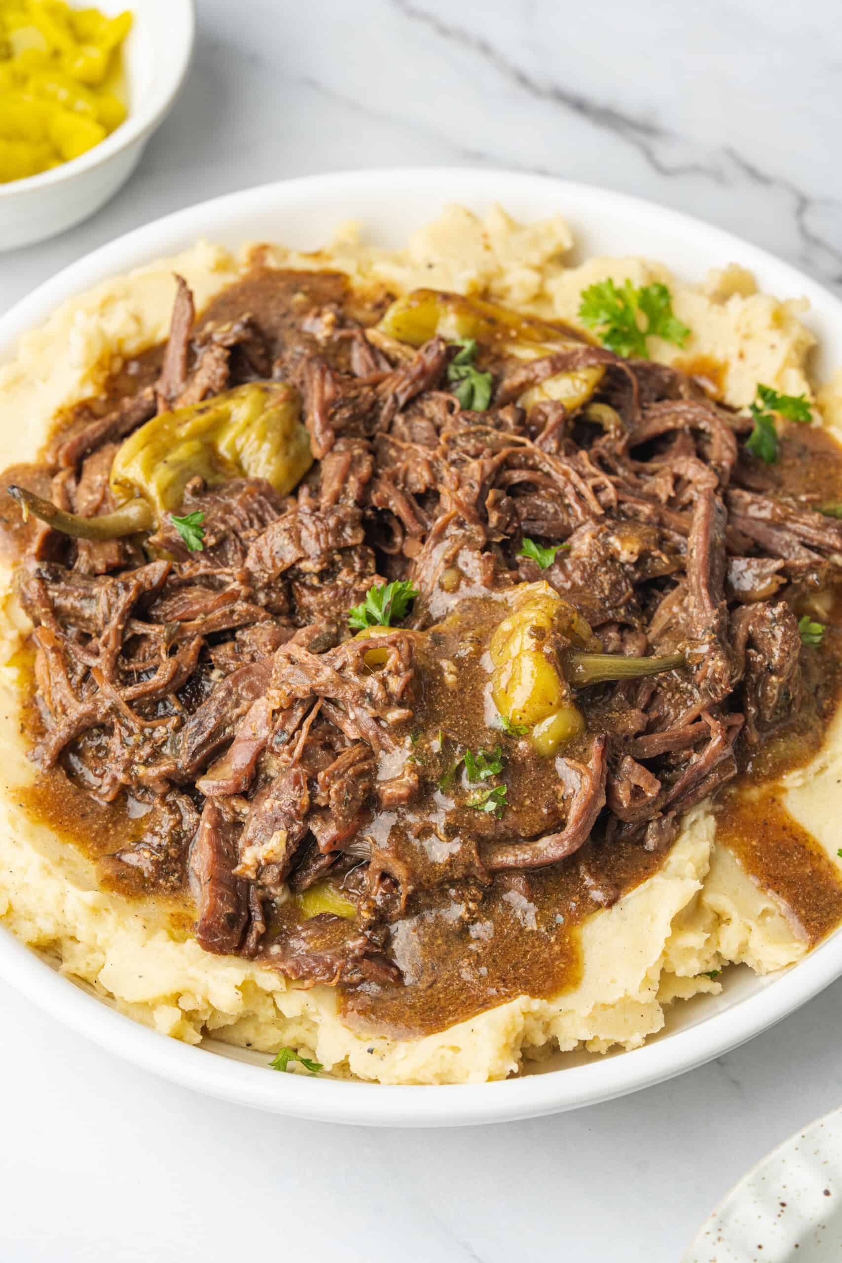 Mississippi pot roast with pepperoncini and gravy served over mashed potatoes.