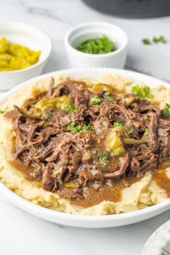 Mississippi pot roast with pepperoncini, gravy, and parsley served over mashed potatoes.