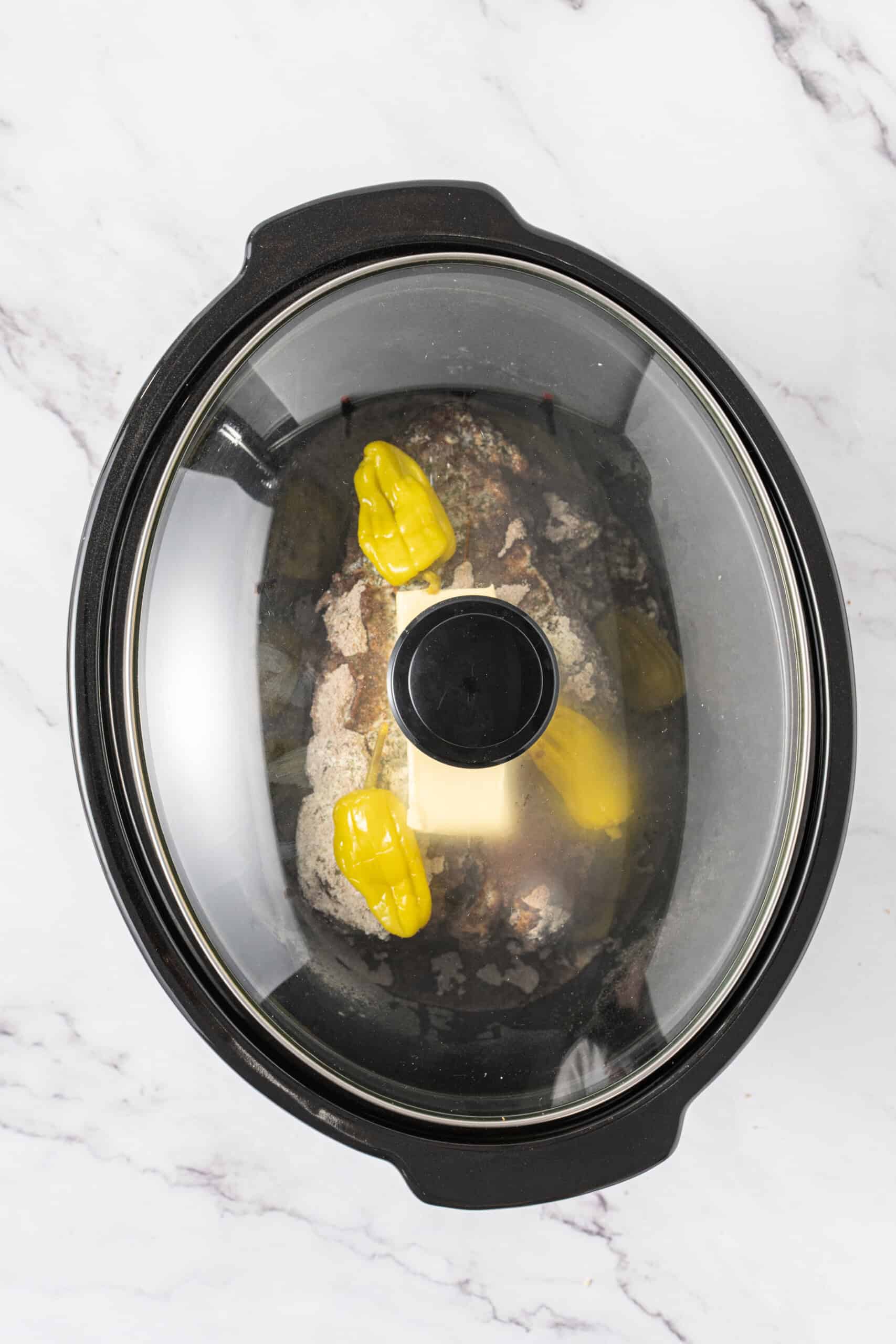Slow cooker covered with a glass lid before cooking the beef roast.