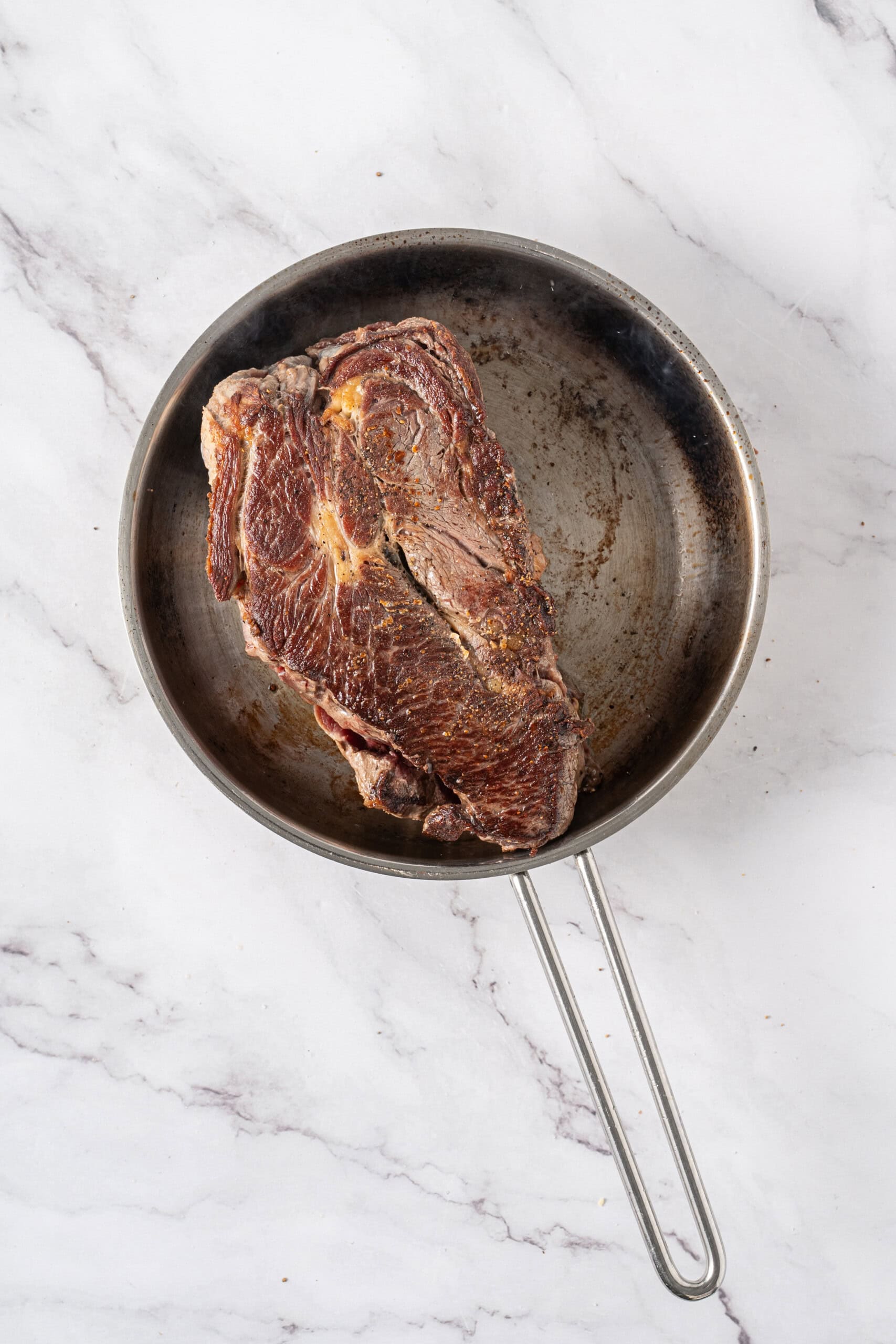 Beef roast seared until browned in a skillet.