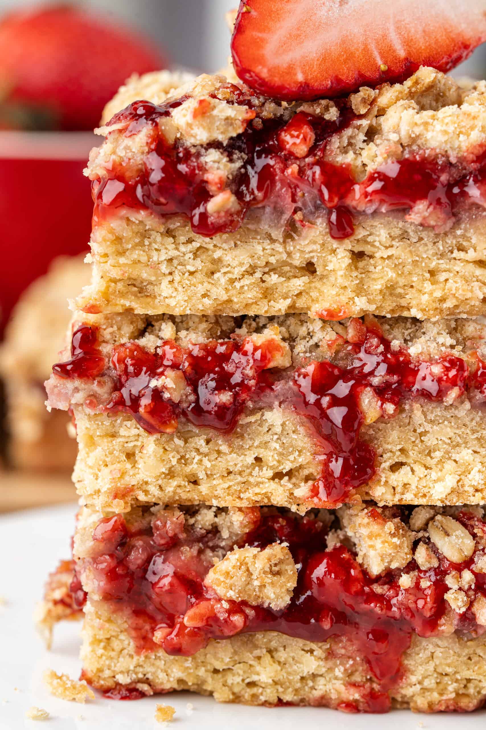 Close-up of stacked strawberry crumb bars with a thick strawberry filling and golden oat crumble.