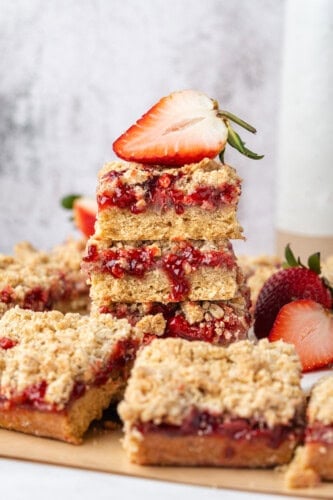 Stacked strawberry crumb bars with strawberry filling, oat crumble topping, and fresh strawberries.