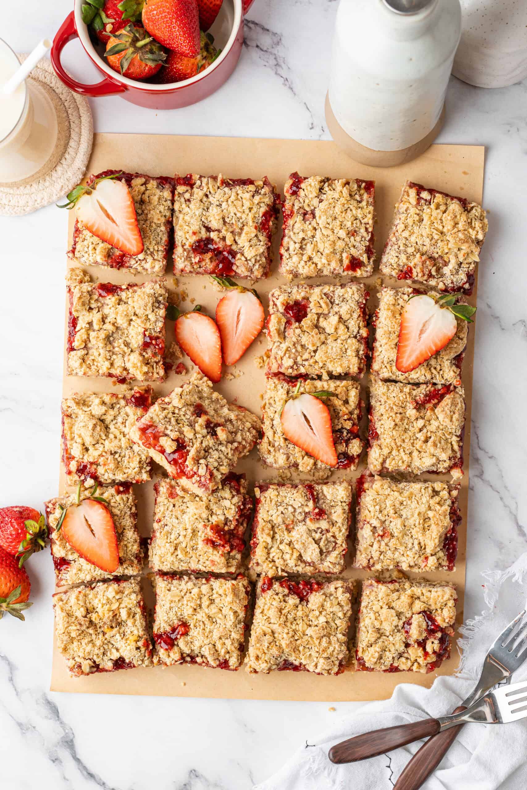 Sliced strawberry crumb bars arranged with fresh strawberries.
