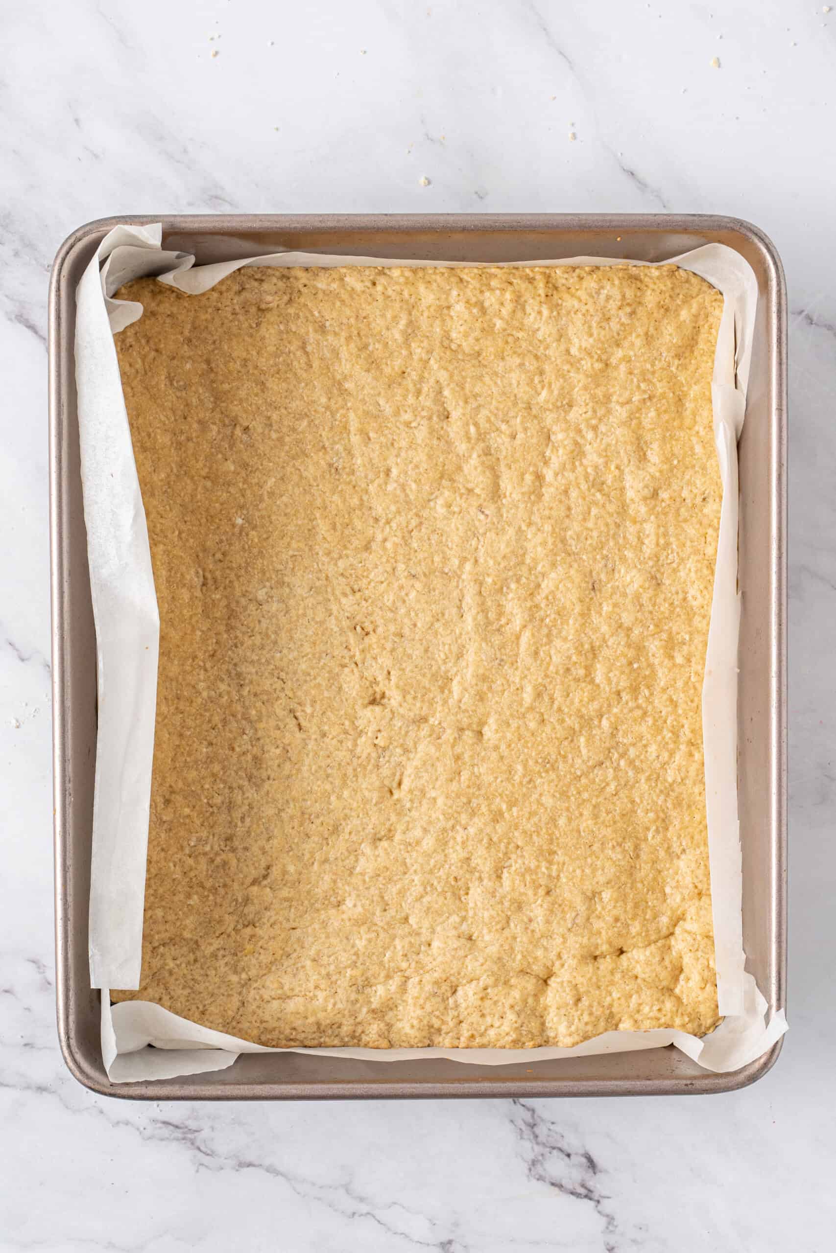 Baked crust in a parchment-lined baking pan.