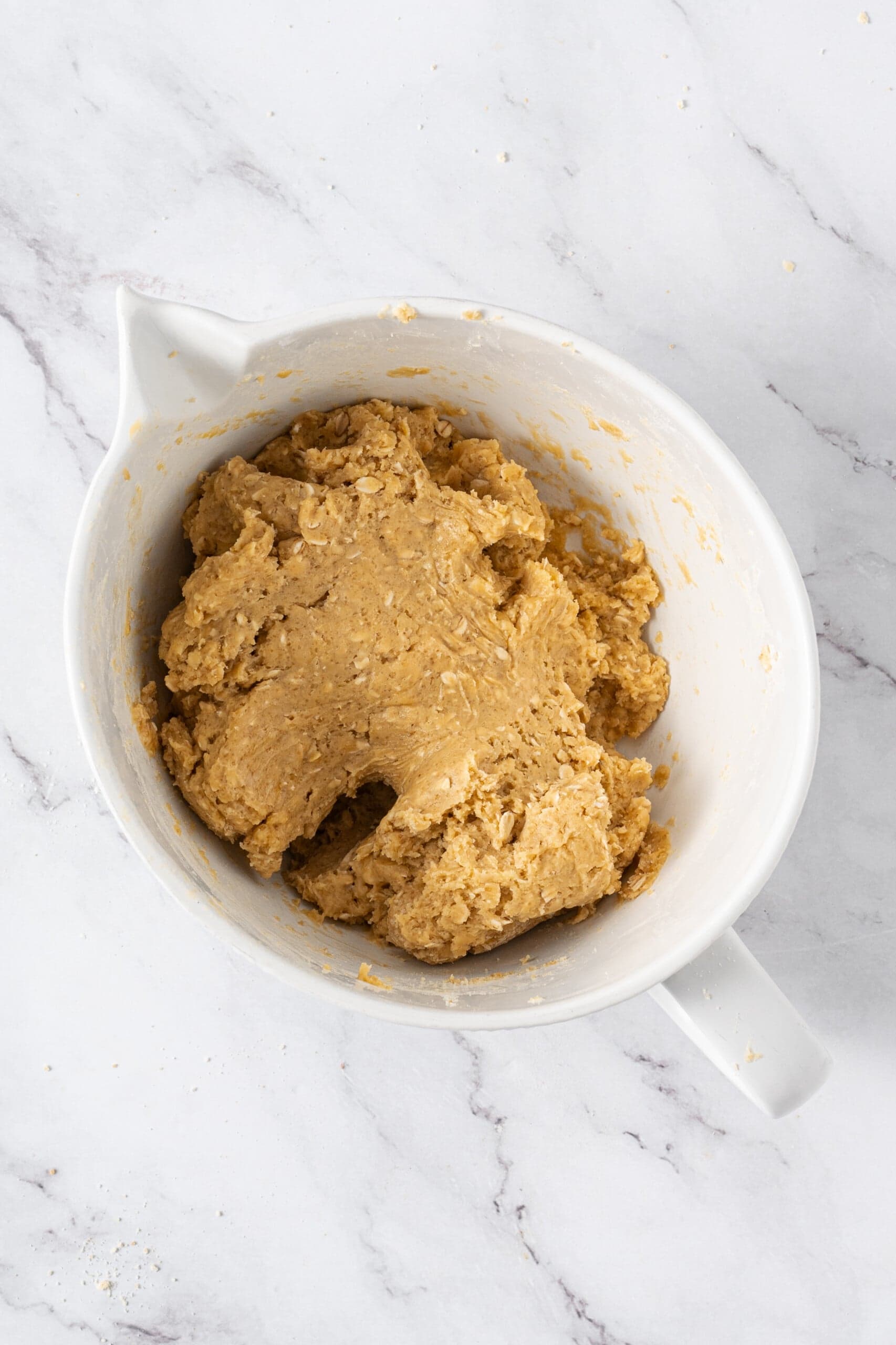 crumble mixture combined into a thick dough in a white mixing bowl.