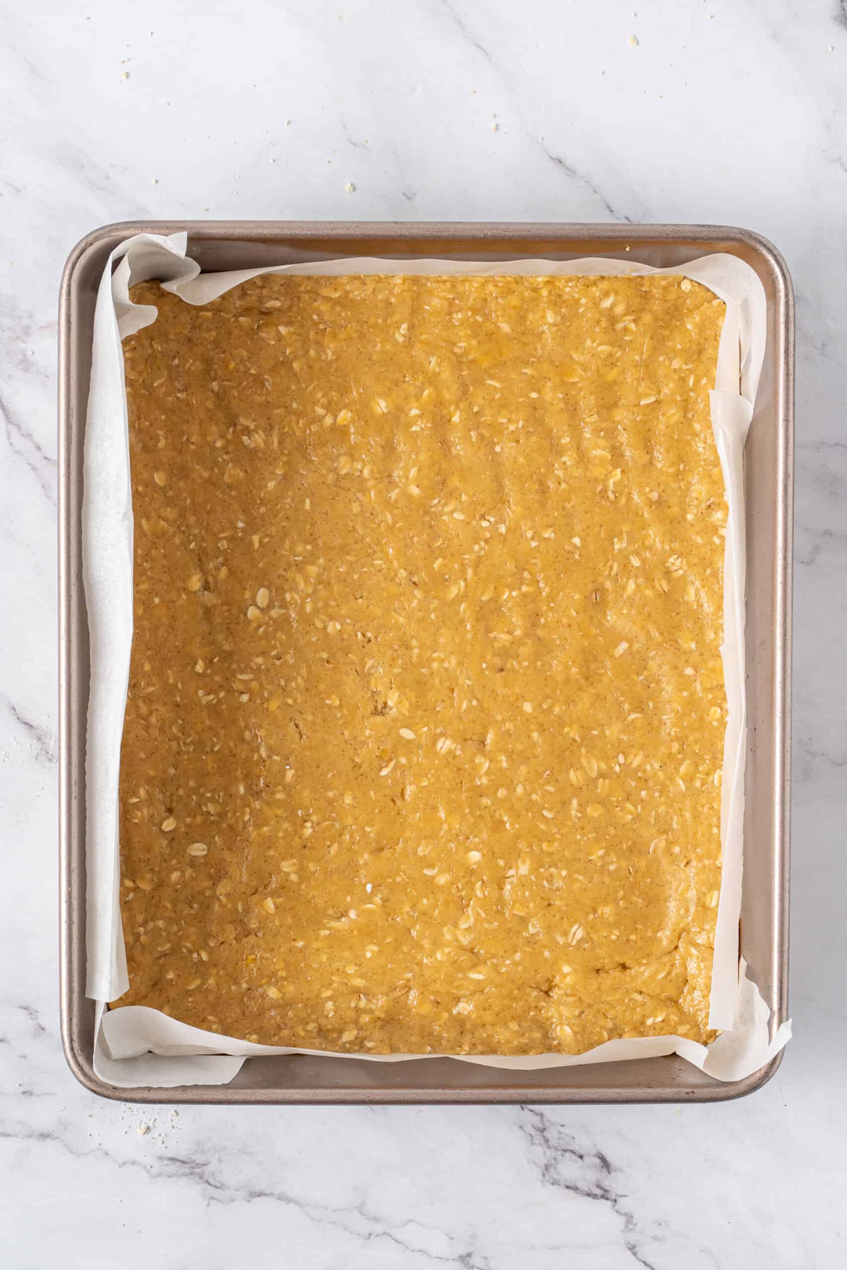 Crumb mixture pressed evenly into a parchment-lined baking pan.