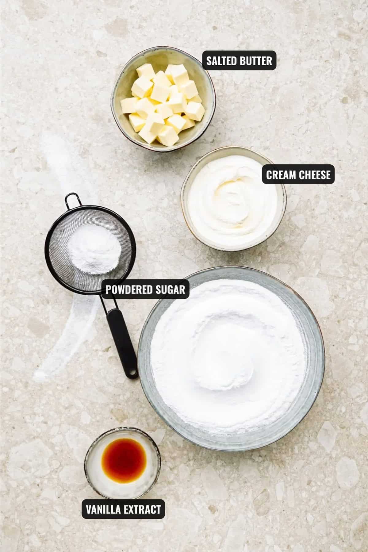 ingredients for butter cream cheese frosting recipe including salted butter, powdered sugar, cream cheese, and vanilla extract