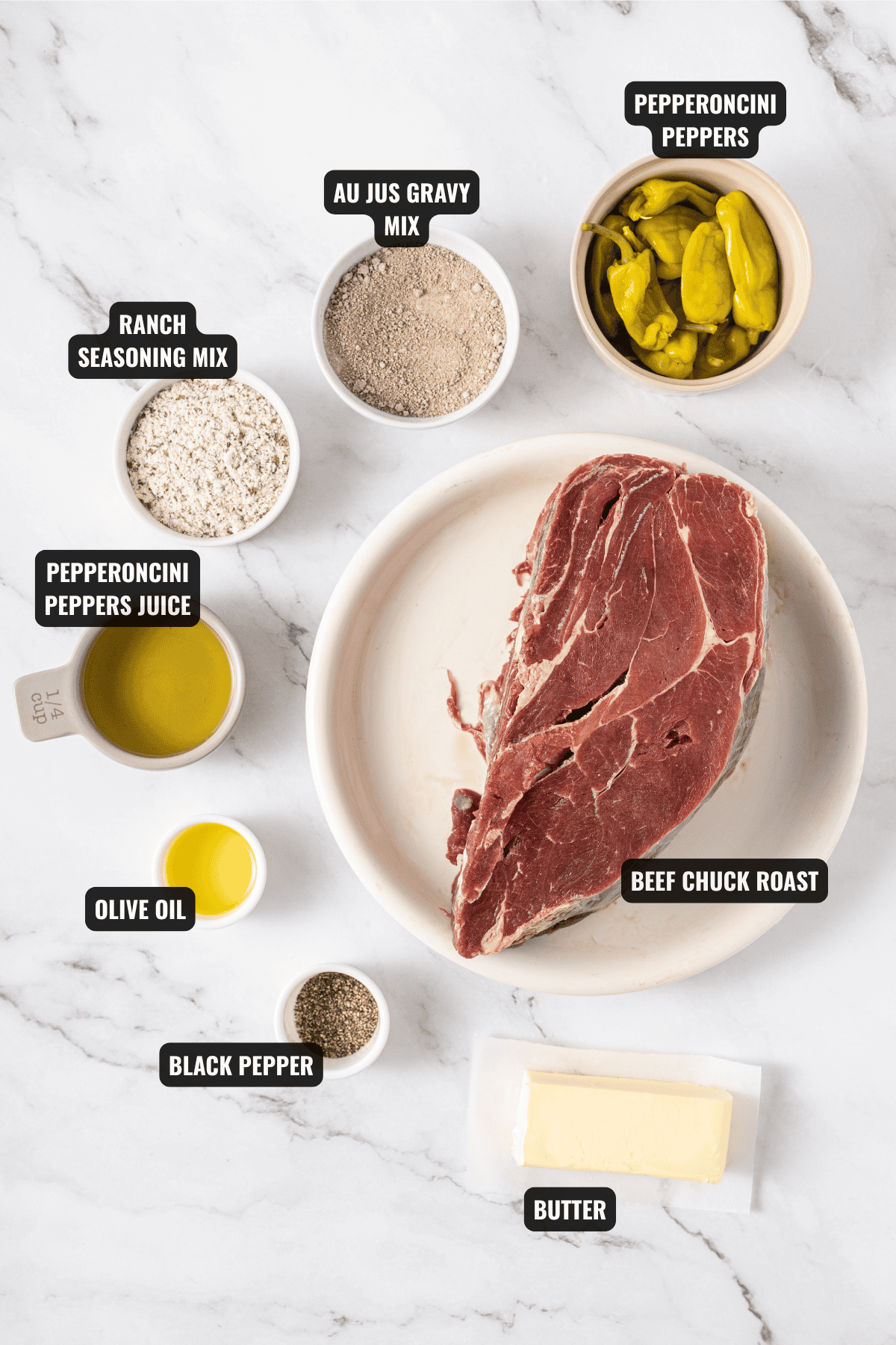 ingredients for mississippi pot roast recipe including beef chuck roast, butter, black pepper, olive oil, pepperoncini peppers, pepperoncini peppers juice, au jus gravy mix, and ranch seasoning mix.