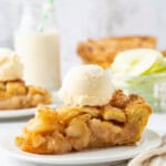 A slice from a homemade apple pie recipe topped with vanilla ice cream, showing tender cinnamon-spiced apples and a golden, flaky crust.