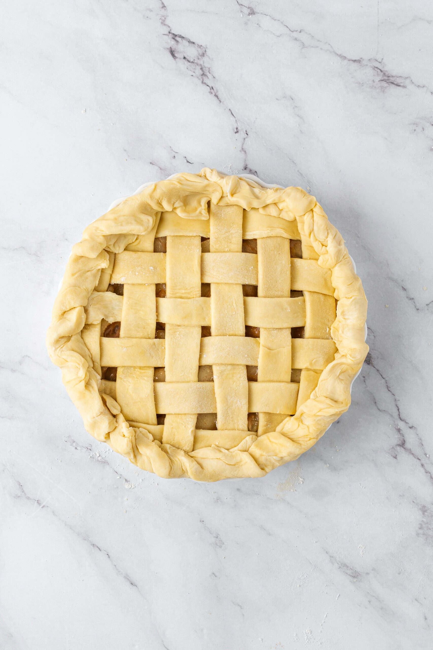 Unbaked pie with a woven lattice crust and thick, folded dough edges in a pie dish.