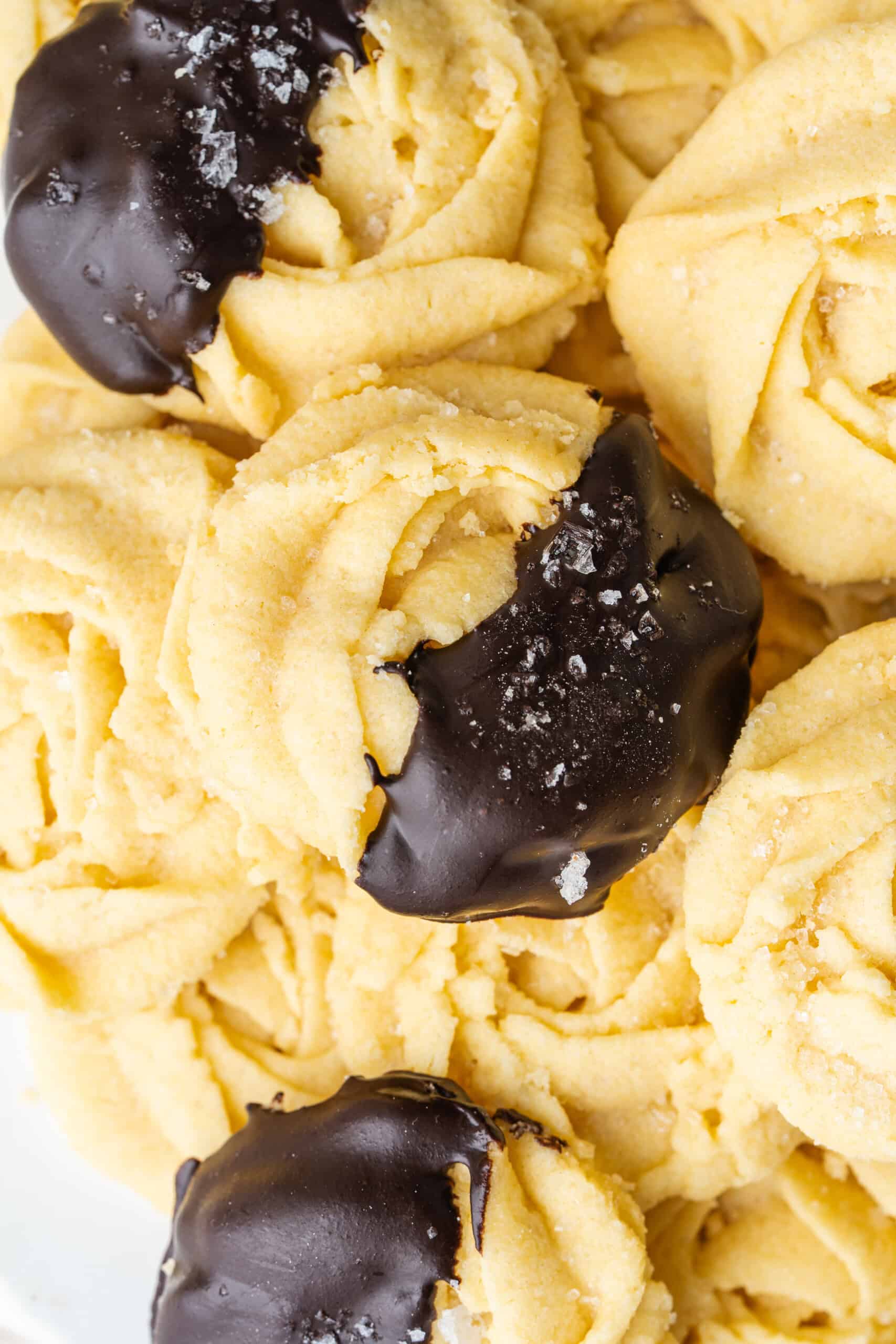 Close-up of butter cookies dipped in dark chocolate and sprinkled with sugar.